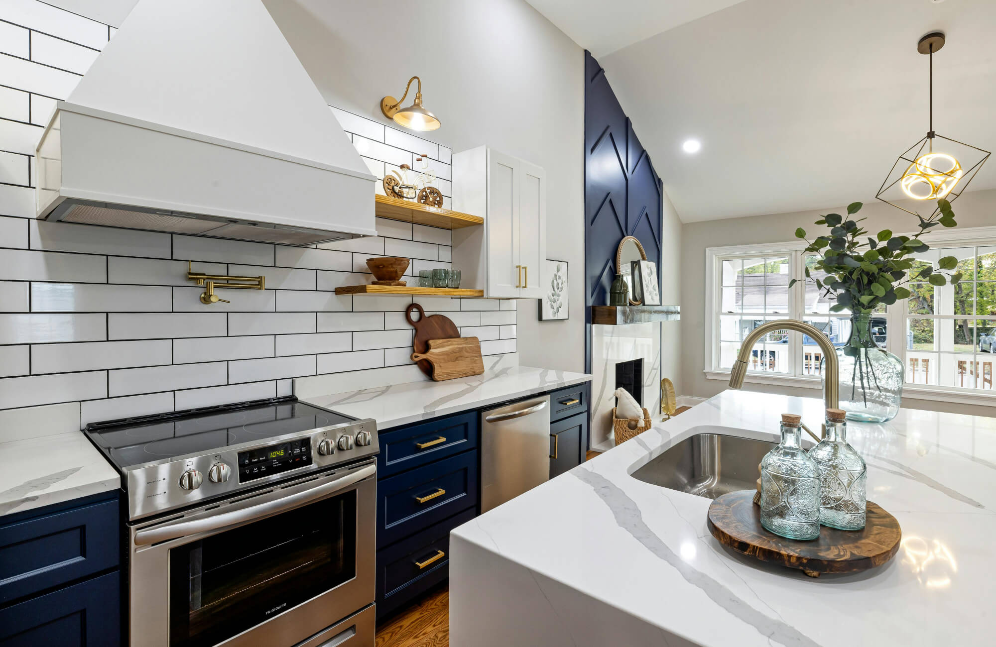 Modern kitchen backsplash with white subway tiles and black grout, paired with navy cabinets, brass hardware, and white quartz countertop.