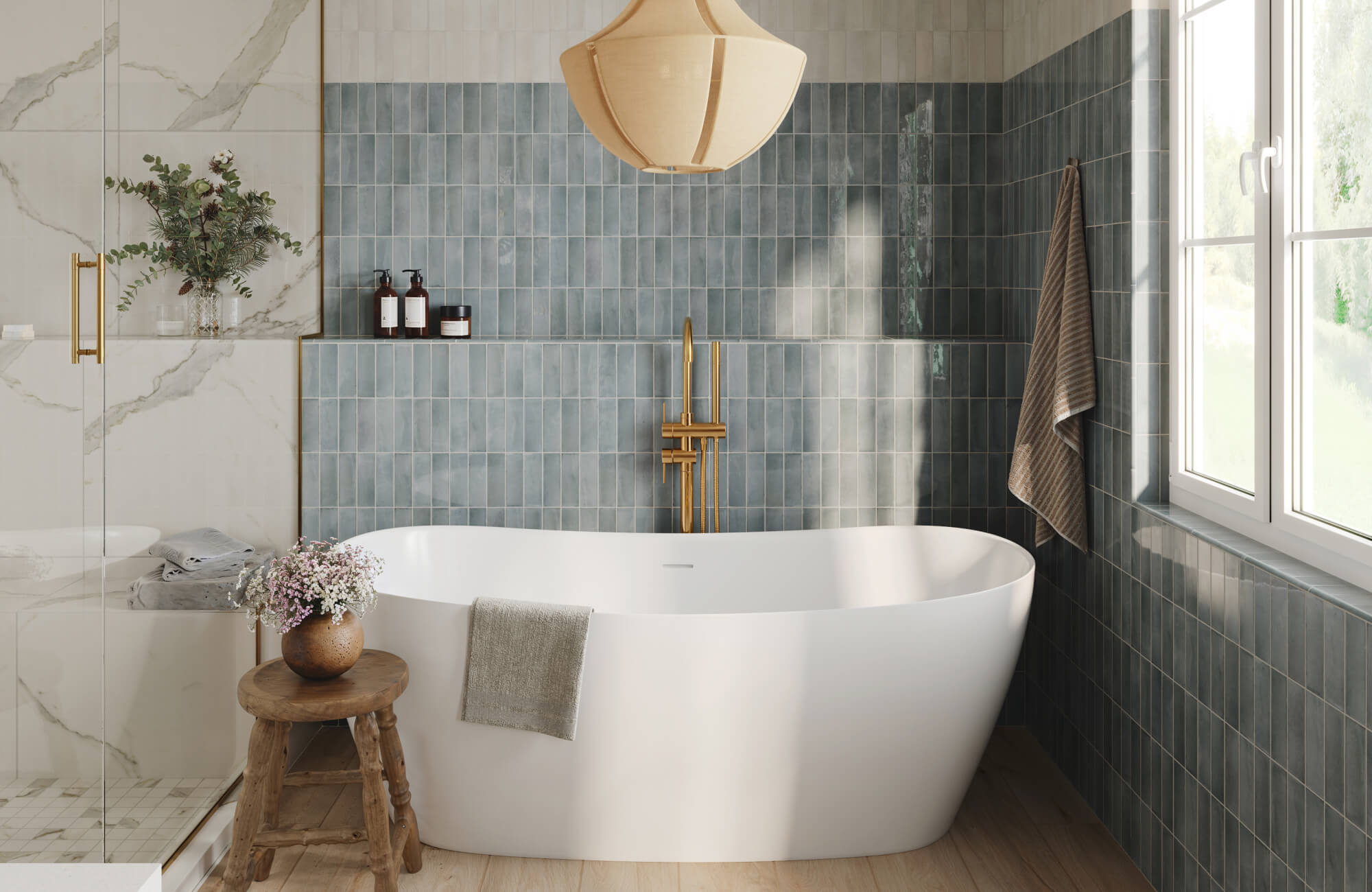 Serene bathroom with a freestanding white soaking tub, blue-gray zellige-style tile walls, brass tub filler, sculptural pendant light, and natural light from a window.
