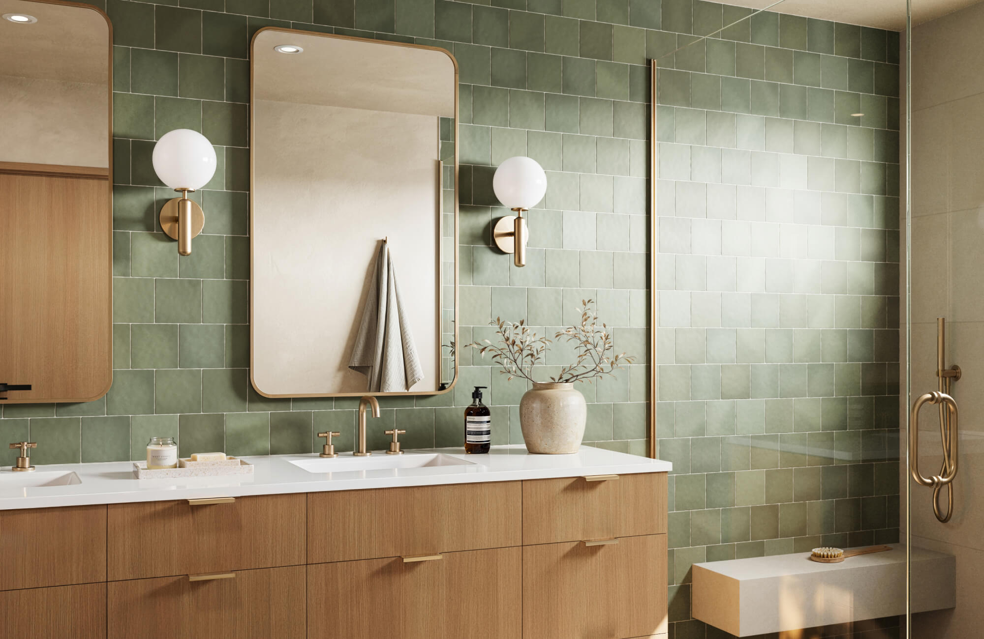 Modern bathroom with a wood vanity, brass fixtures, rounded mirrors, globe wall sconces, and green zellige-style tile walls in the shower area.