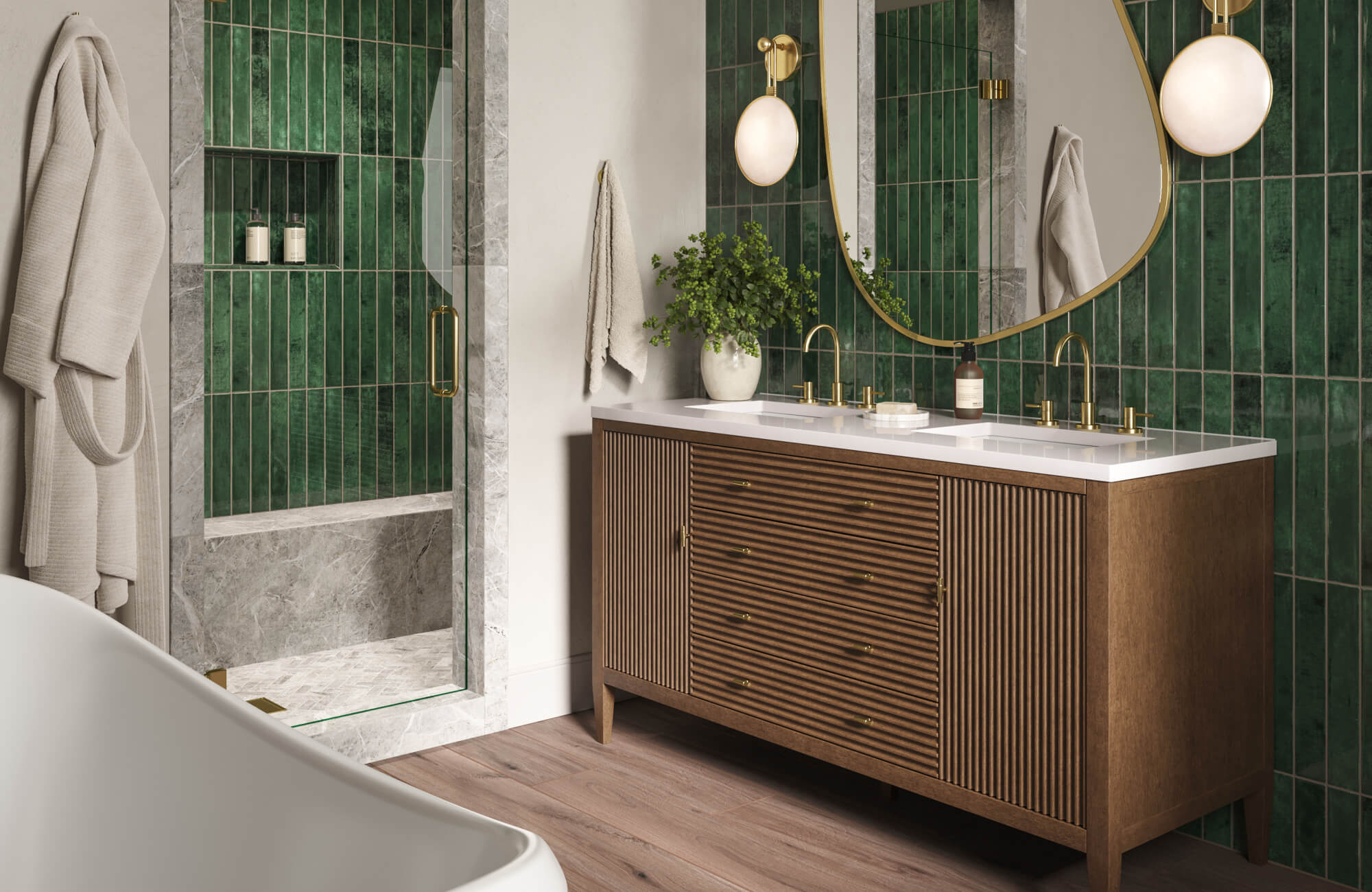 Elegant bathroom with a wood vanity, brass fixtures, curved mirror, globe wall sconce, marble shower surround, and deep green zellige-style tile walls.