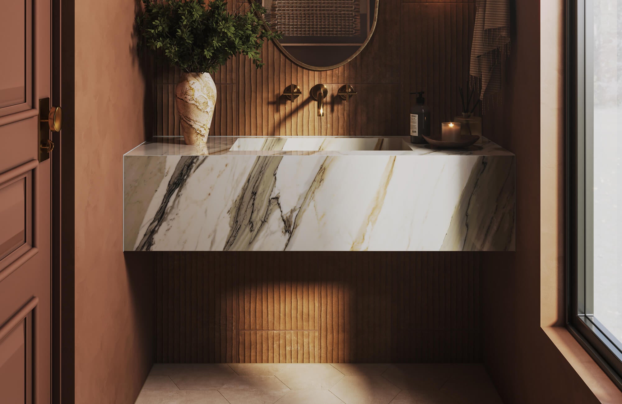 Sculptural floating washbasin in bold-veined marble look tile, paired with vertical terracotta tiles and warm brass fixtures.