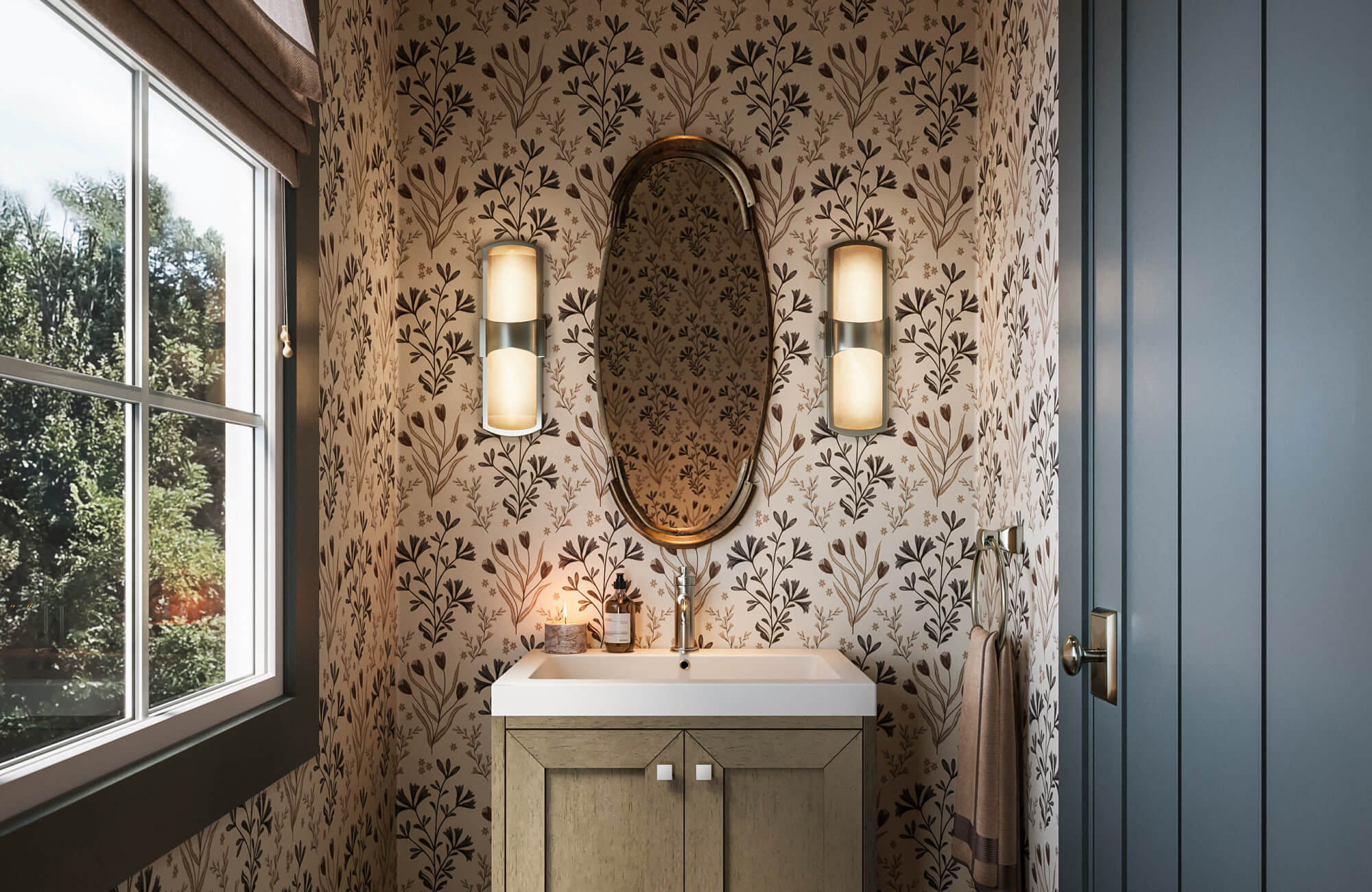 Charming powder room with botanical wallpaper, oval brass mirror, warm sconces, and a light wood vanity with white sink.