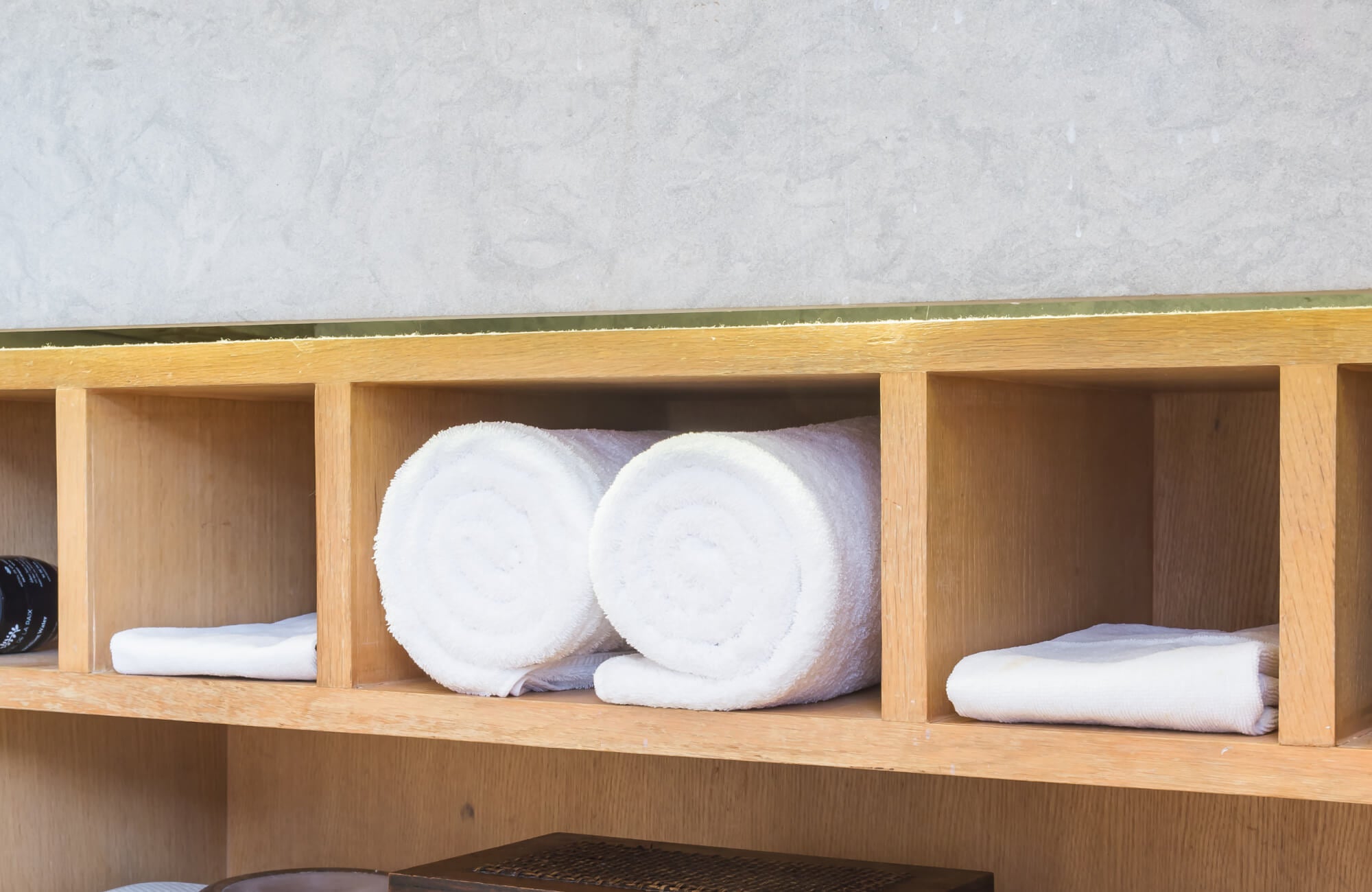 A diy bathroom remodel detail showcases built-in wooden cubbies neatly holding rolled white towels, blending practical storage with a clean, spa-like look in the bathroom.