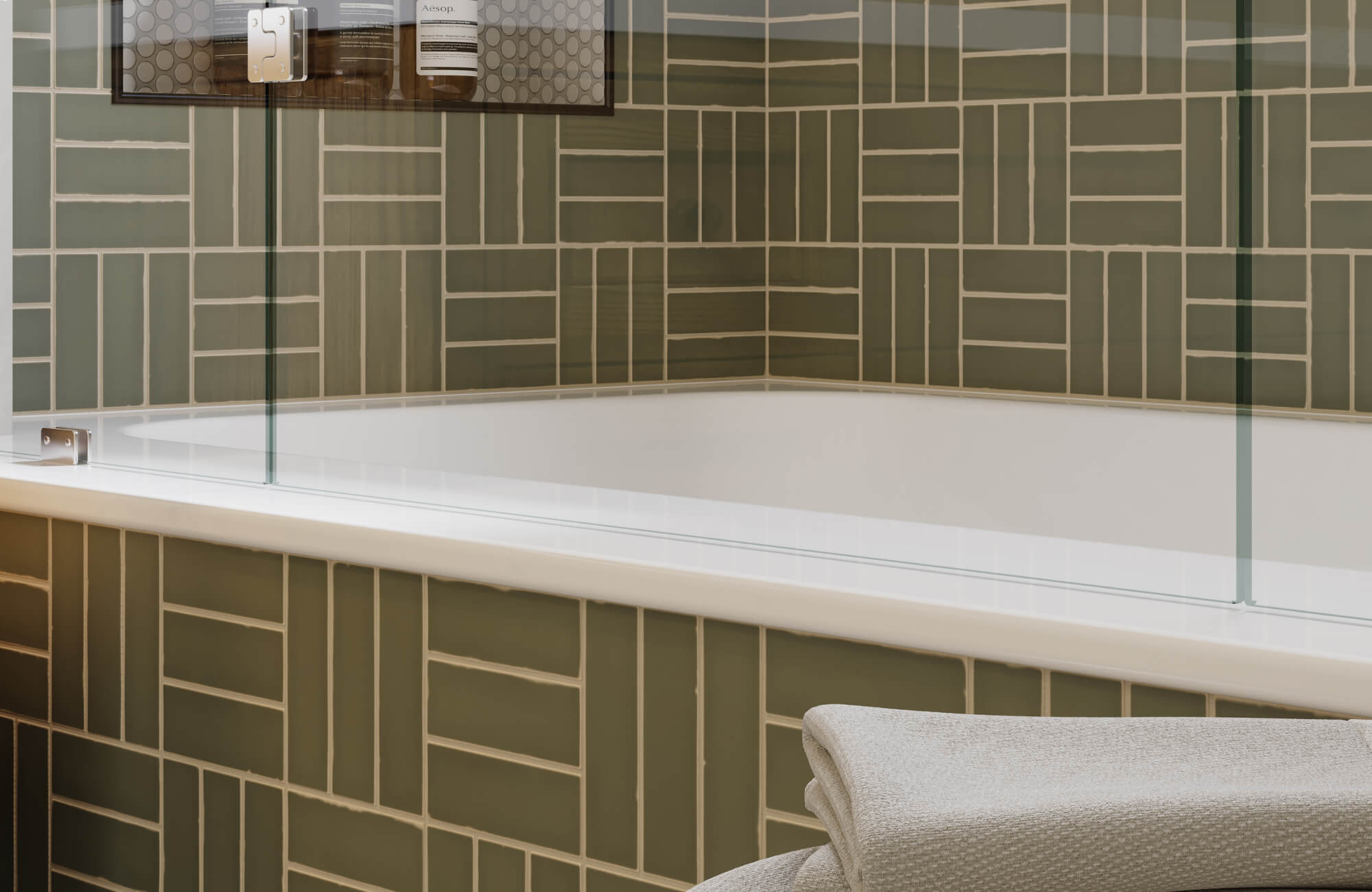 null Bathtub surround with handmade geometric tiles, glass shower panel, and neatly folded textured towels.