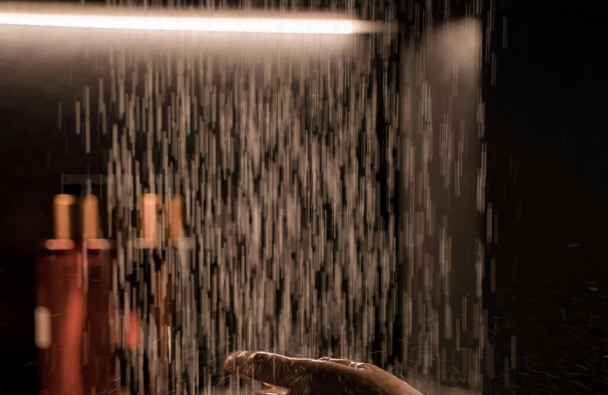 null Contemporary bathroom renovation detail highlighting a rainfall shower with cascading water, ambient lighting, and minimalist shelving that enhances the luxurious, spa-like shower experience.