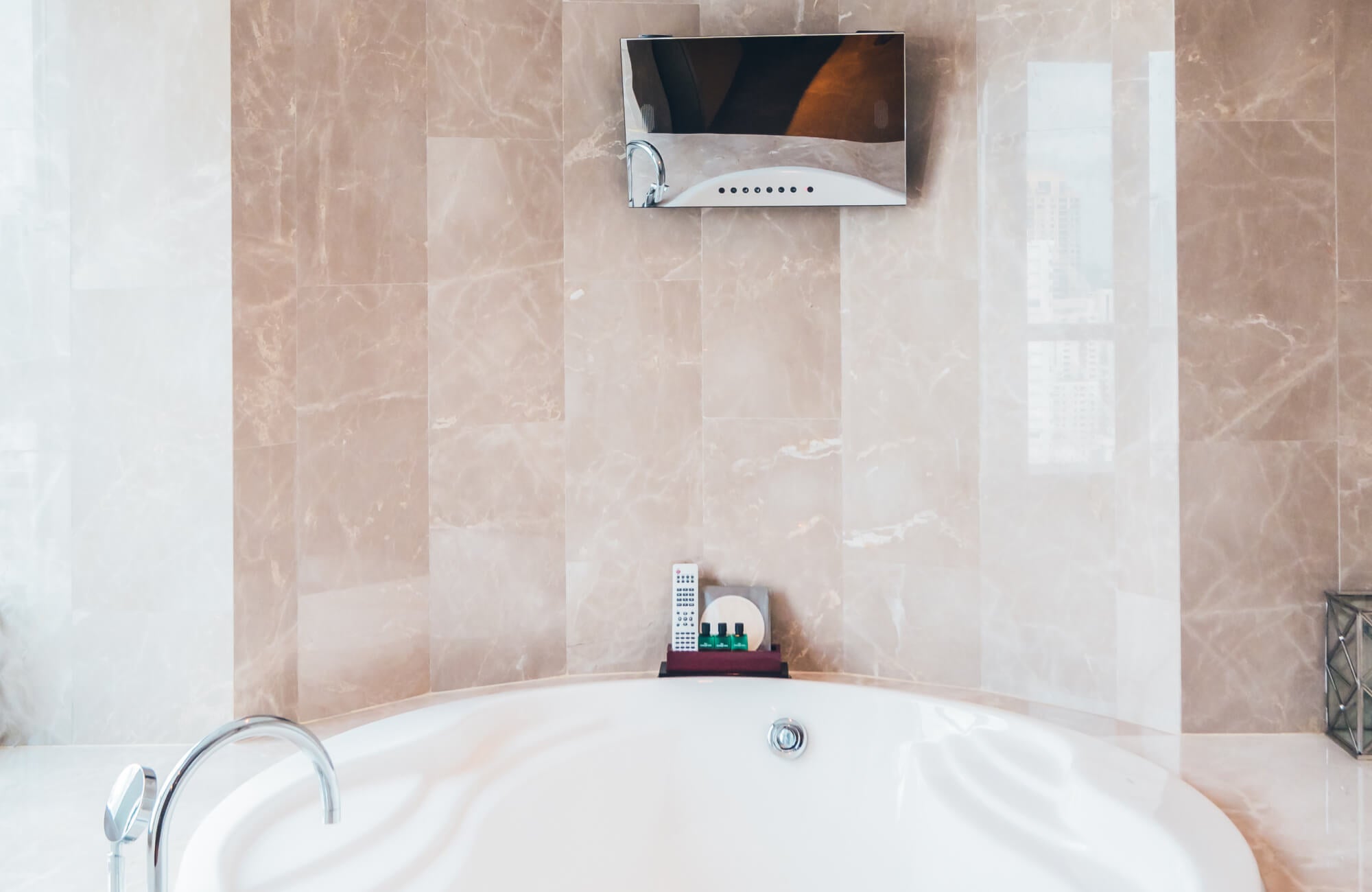 null Modern bathroom renovation featuring a sleek built-in soaking tub set against large-format beige marble wall tiles, integrated chrome fixtures, and a wall-mounted mirror that enhances the clean, contemporary aesthetic.