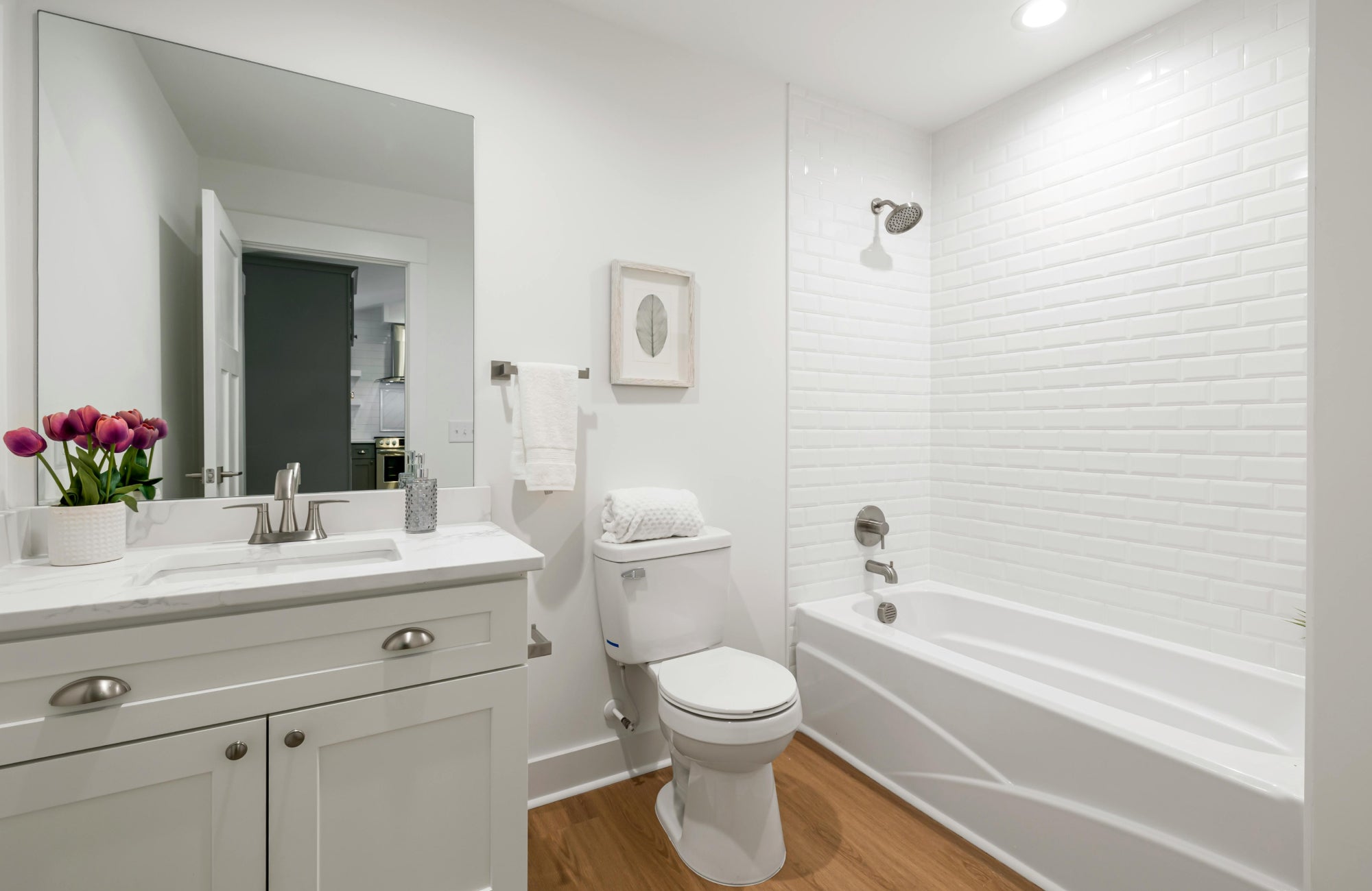 null White subway tile shower with glossy beveled finish and brushed nickel fixtures.