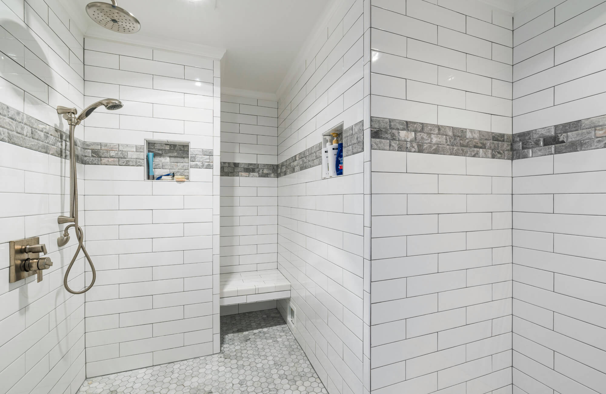 null Walk-in shower with white subway tiles and a gray stone accent band running horizontally across the walls.