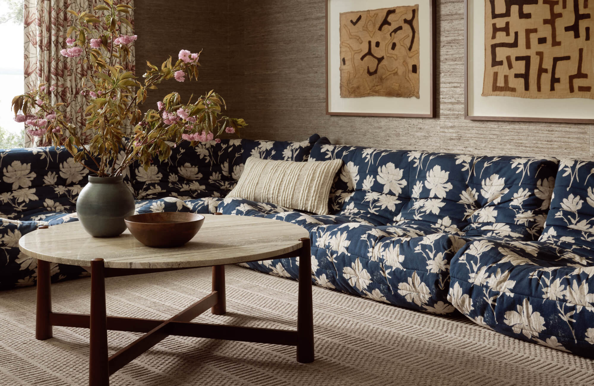 null Navy floral sectional with striped accent pillow on woven neutral rug in cozy, layered seating area.