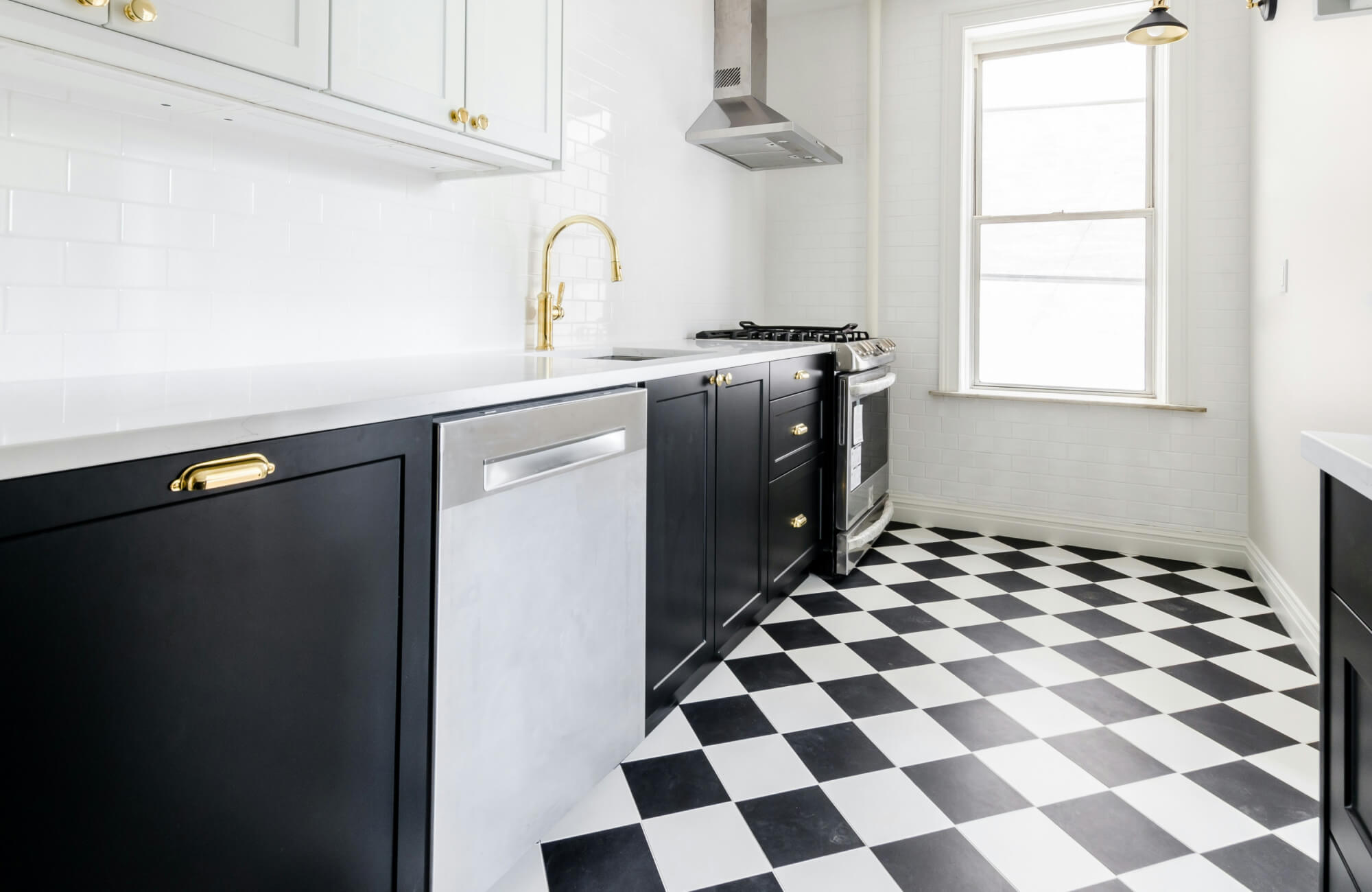 Bright hallway featuring classic black and white checkered floor tiles, with modern wooden benches and white columns enhancing the space’s airy feel.