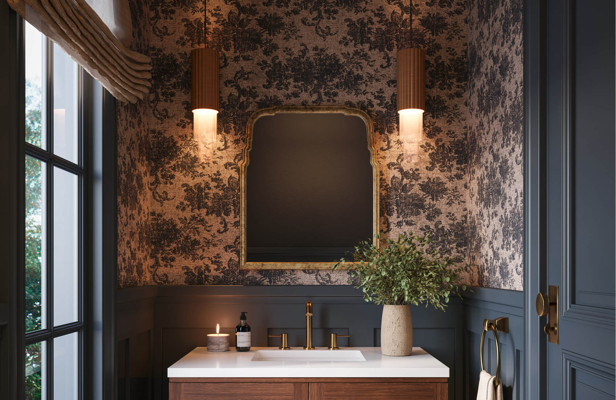 Moody powder room with dark botanical wallpaper, brass fixtures, sculpted mirror, and warm pendant lighting.