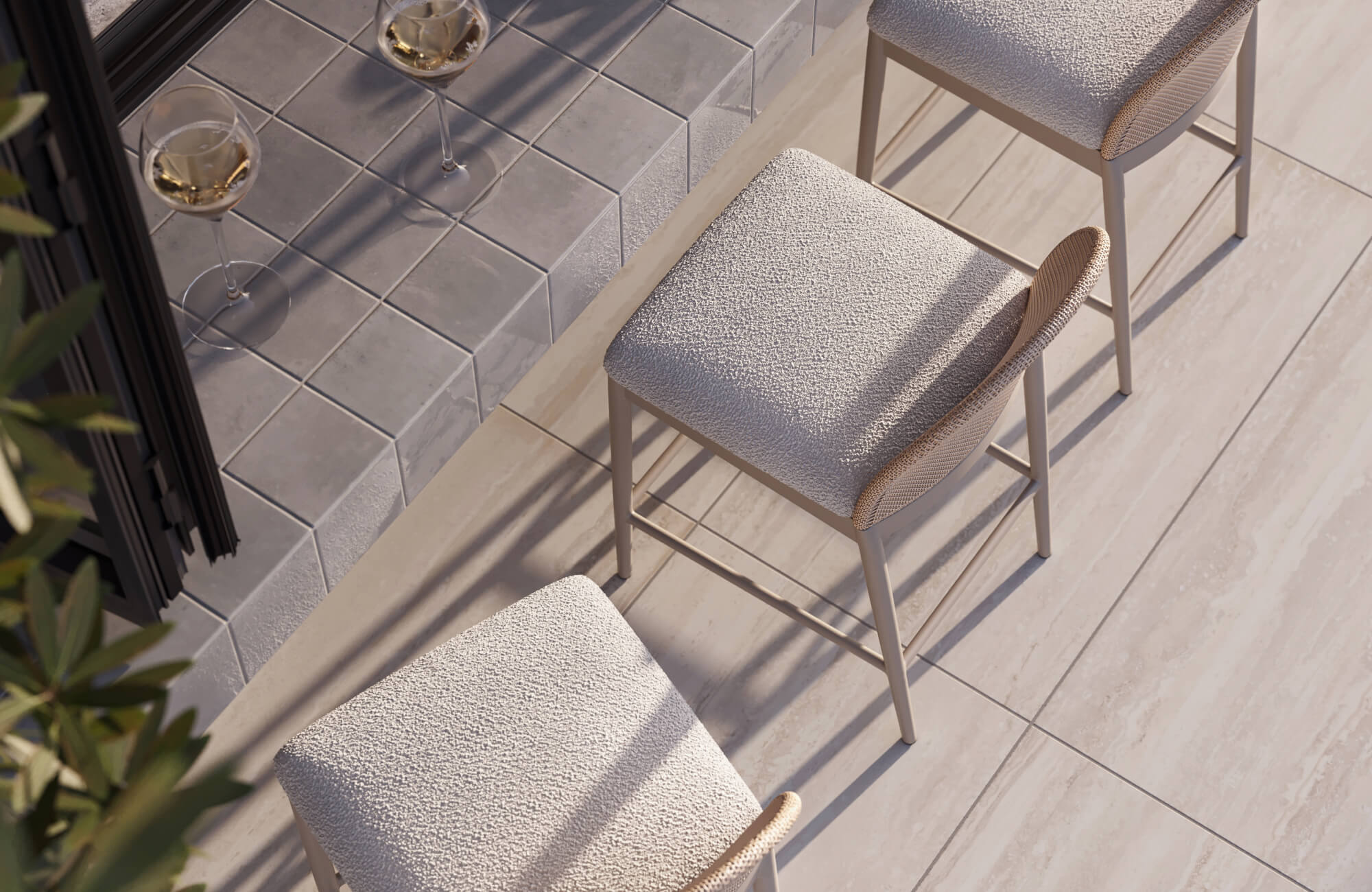 null Next to a tiled ledge, soft gray cushions on light beige stools rest over pale gray tiles, illustrating how cushions improve comfort in outdoor spaces.