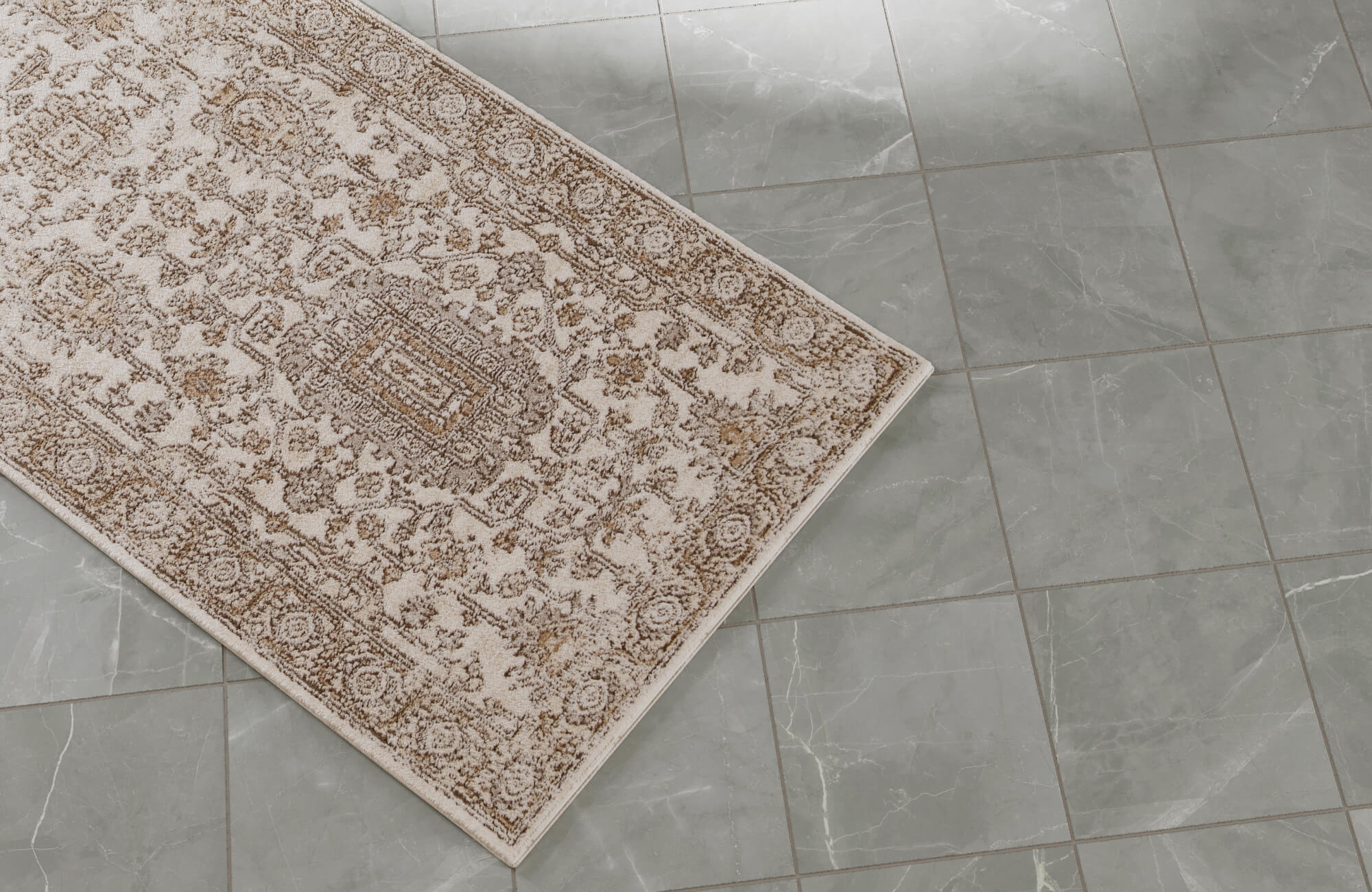 Traditional patterned rug in soft beige and warm brown tones placed on polished gray stone tiles.