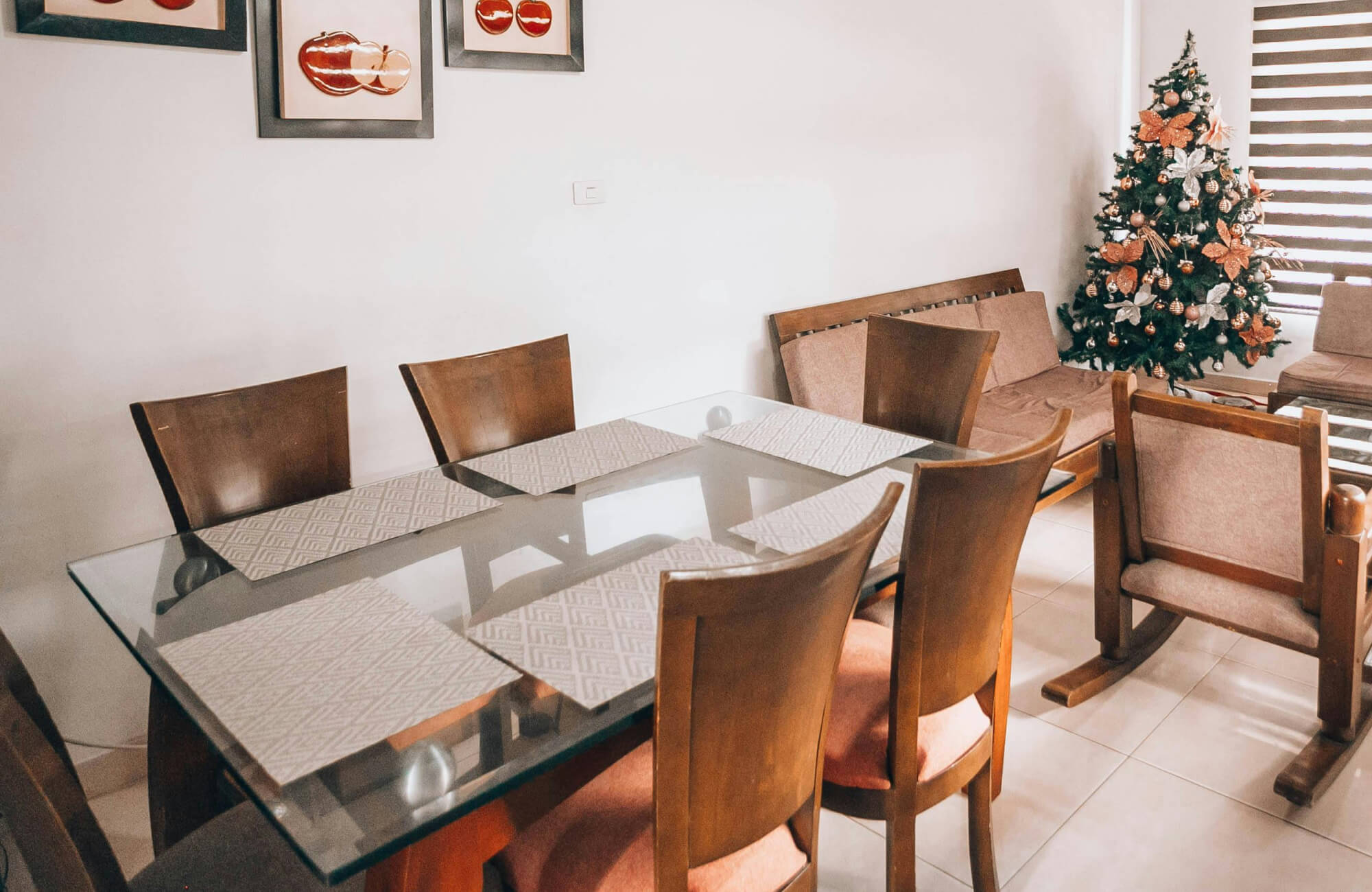 null A warm, inviting dining room featuring a rectangular glass dining table paired with solid wood chairs, where the transparent tabletop lightens the space while seasonal décor and natural wood tones create a cozy, lived-in ambiance.