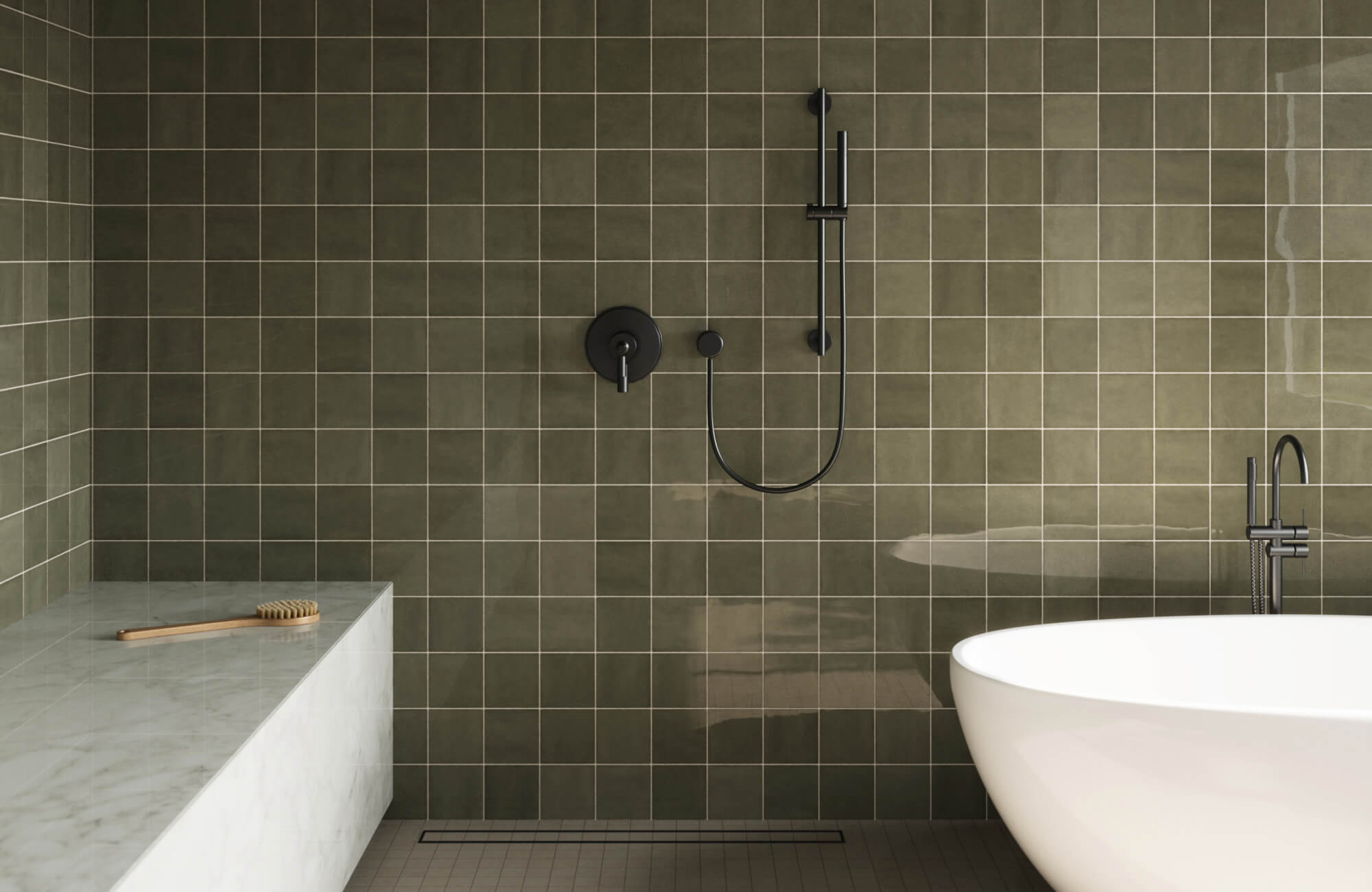 Modern bathroom with matte green square wall tiles, black shower hardware, and a freestanding white tub beside a marble bench.