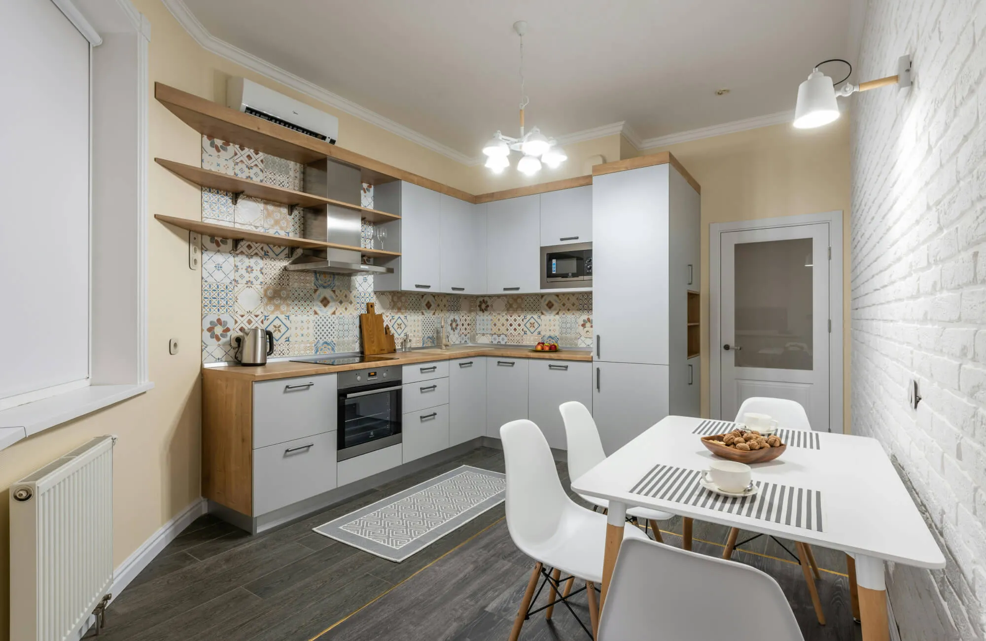 Modern kitchen with patterned backsplash, light gray cabinets, and a slim runner rug placed along the cooking area.
