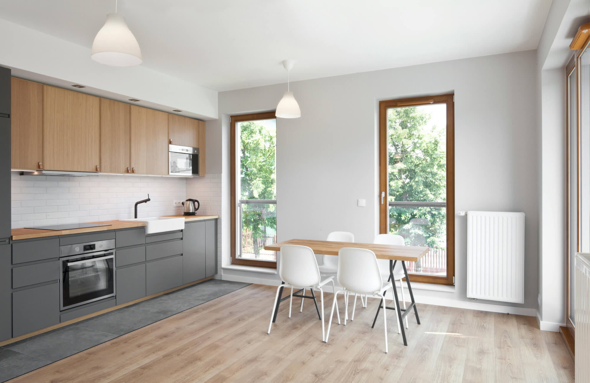 Minimalist kitchen with gray cabinets, wood accents, and a long neutral runner rug placed in front of the sink and oven.