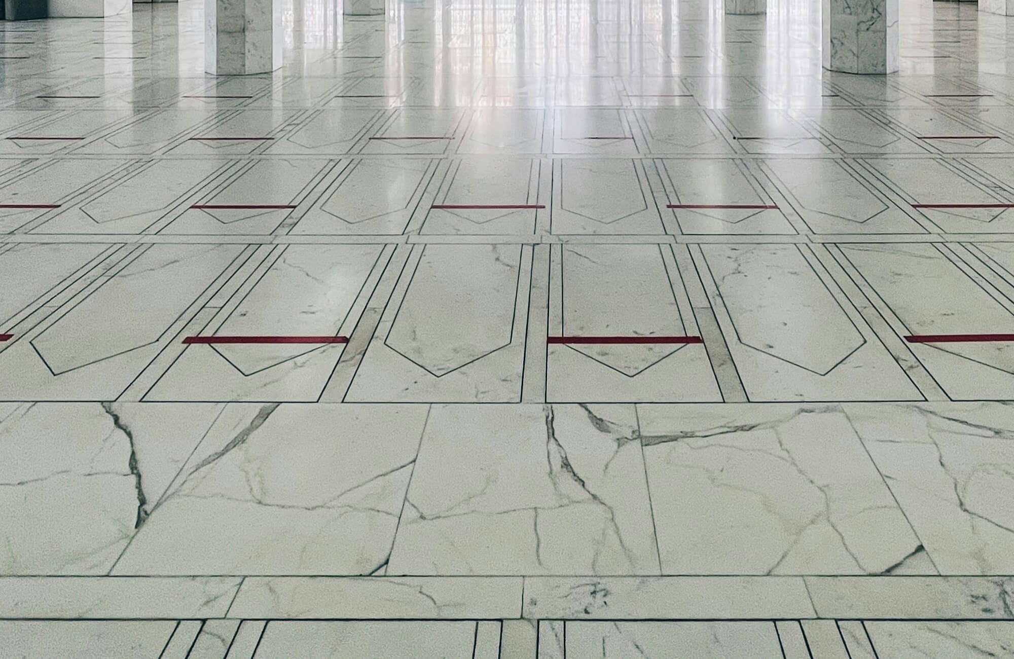 null Expansive marble floor with geometric patterns and subtle red accents, adding elegance to a grand, open space.