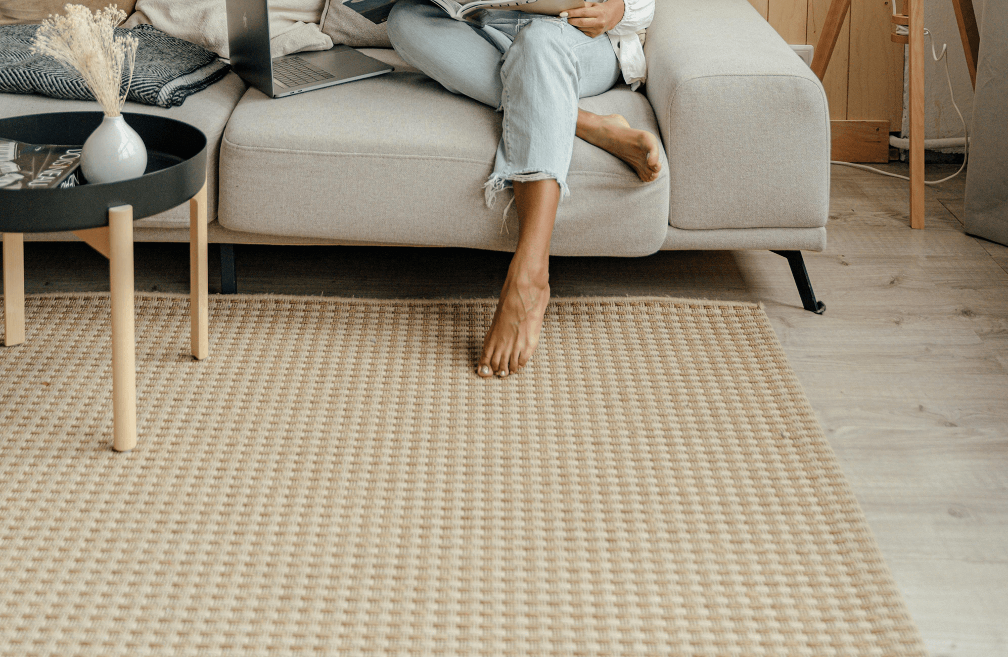 Cozy living space with light wood flooring, a rug, and a modern beige sofa for relaxed comfort.