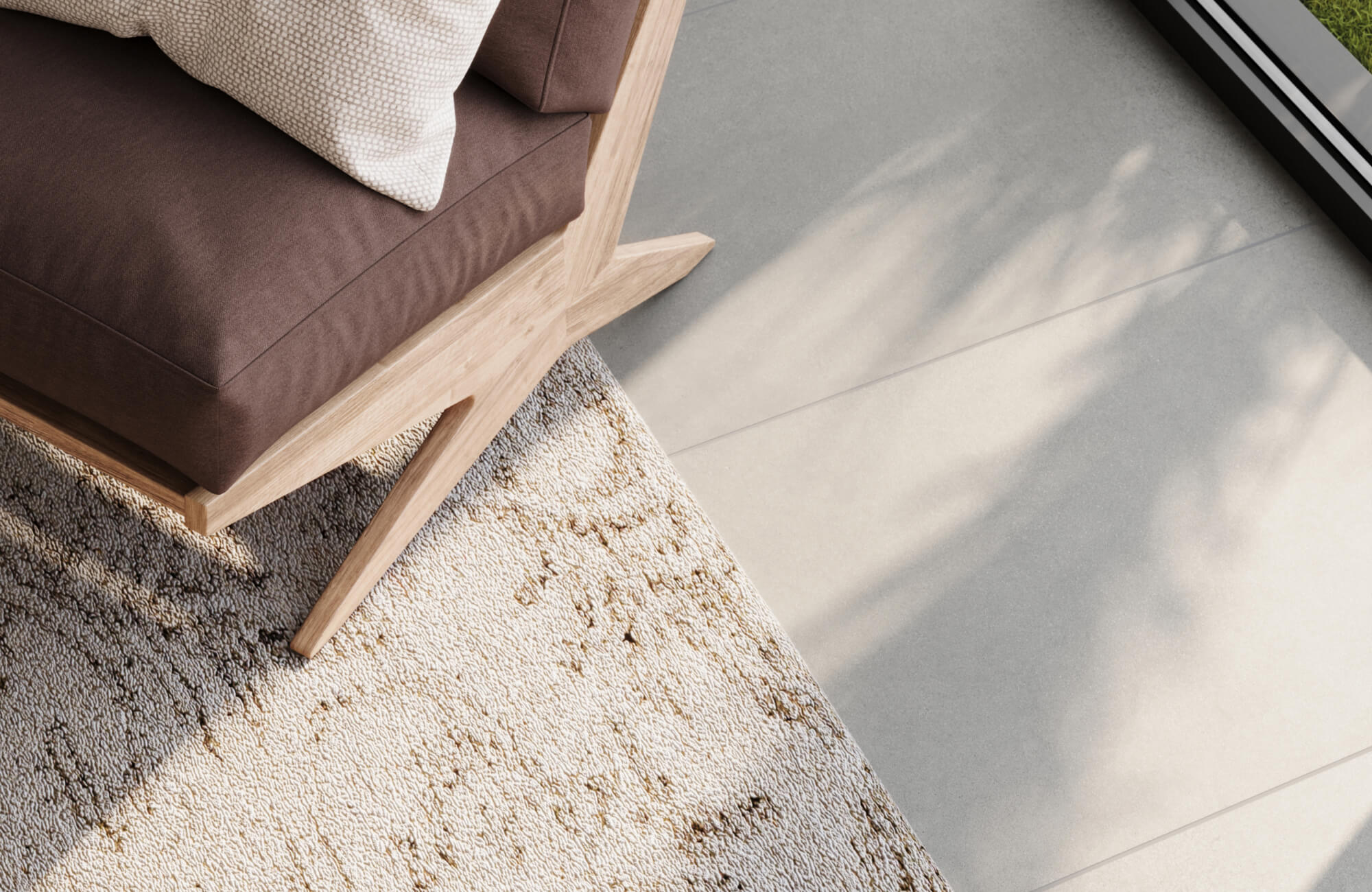 Close-up of a cream and beige polypropylene rug beneath a modern wooden armchair, basking in soft natural light through large windows.