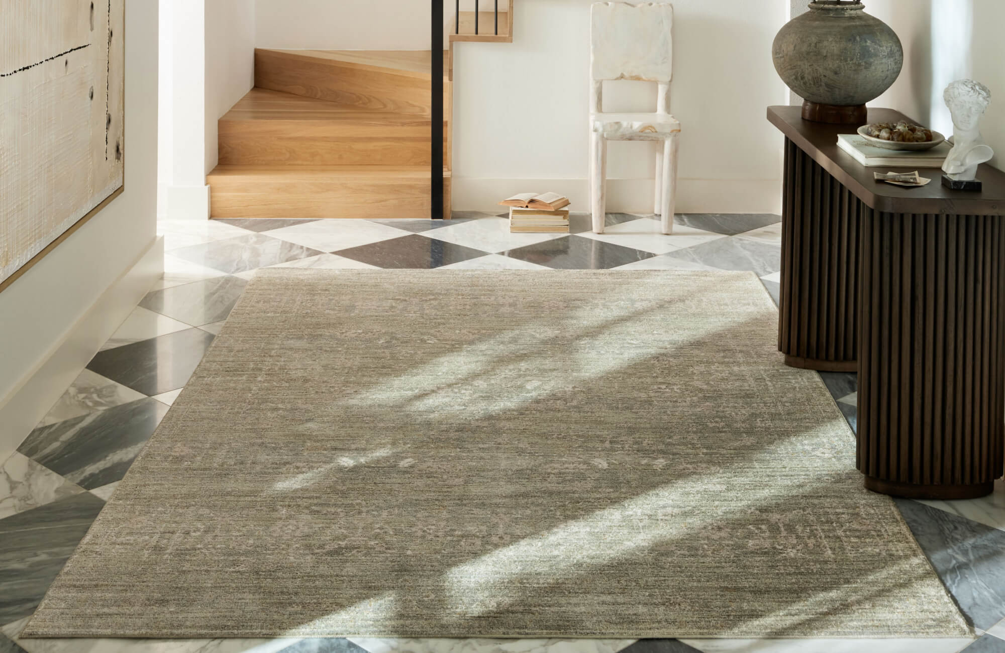 Sophisticated hallway with a soft-toned polypropylene rug layered over bold marble tile flooring, bathed in natural light.