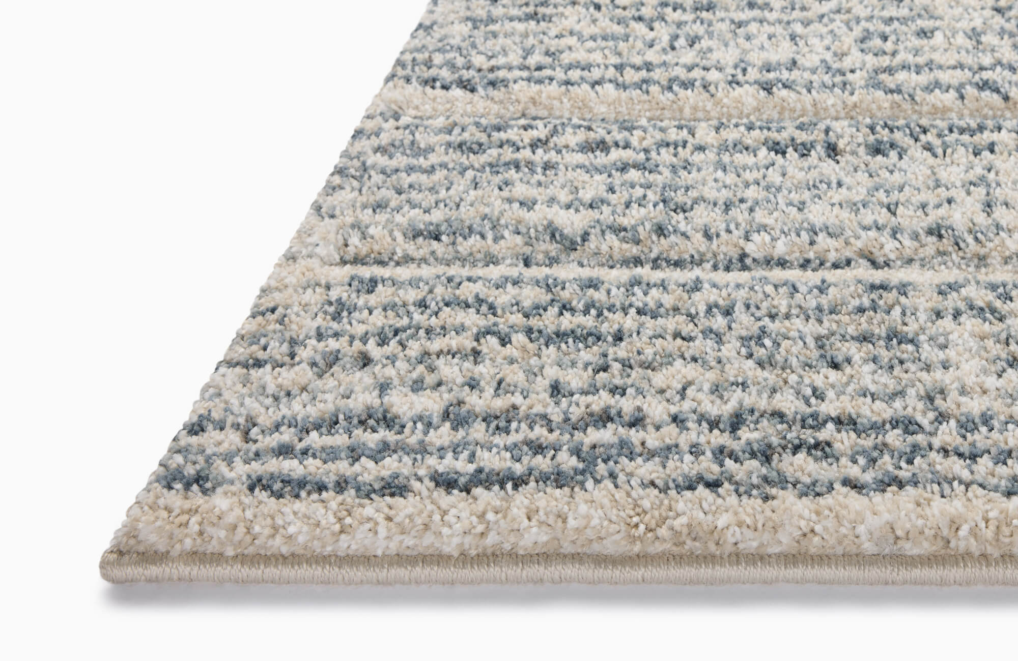 Angled close-up of a plush polypropylene rug with blue and cream stripes, featuring a soft texture and neatly finished edge.