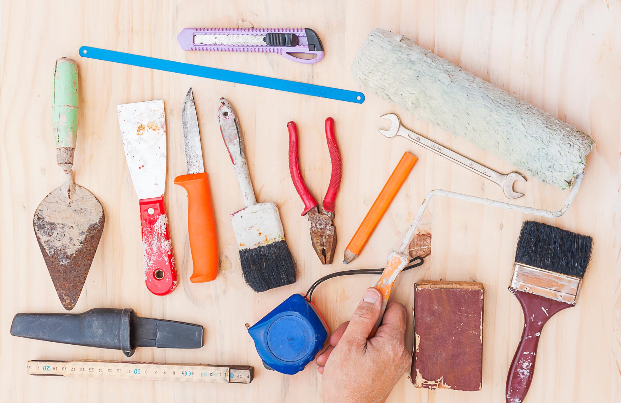 null Essential tools for subway tiling installation, including a trowel, measuring tape, spacers, and brushes, are laid out on a wooden surface.