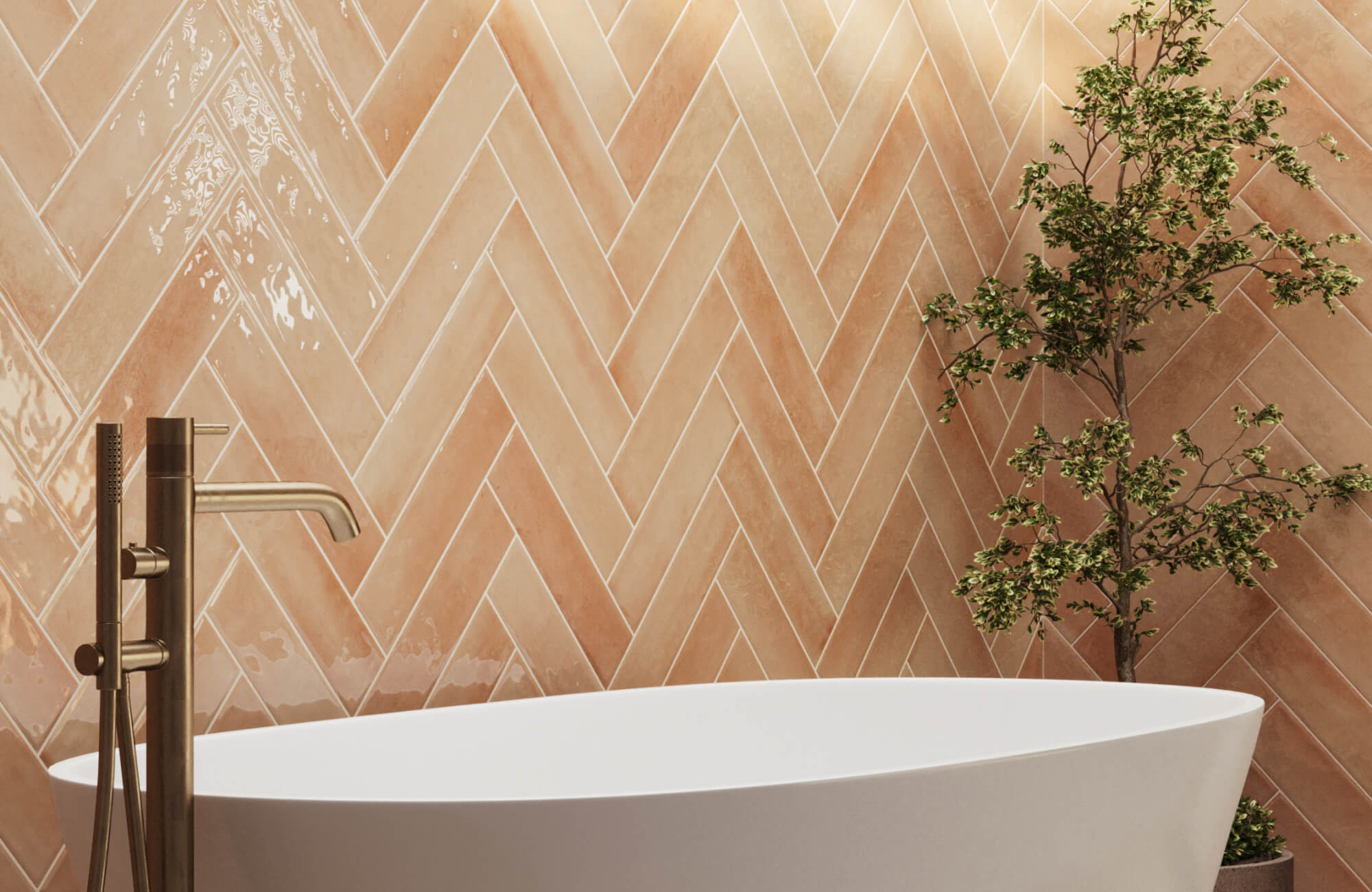 null Herringbone terracotta tiles with a glossy finish create a sunlit focal wall, paired with a sleek white tub, brass hardware, and a potted tree.