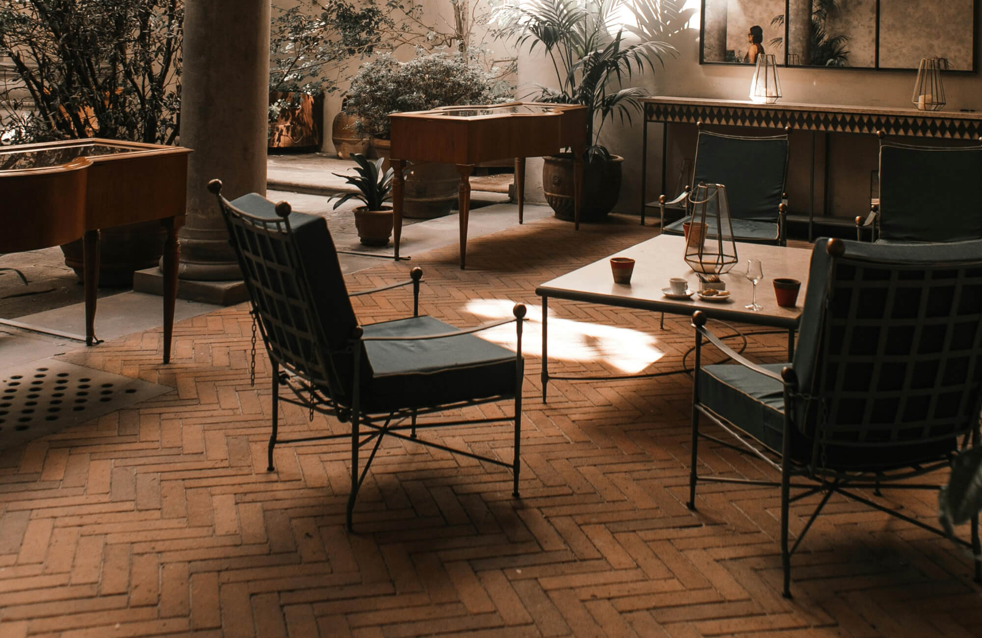 null Cozy indoor lounge with herringbone terracotta flooring, complementing dark metal chairs and warm lighting.
