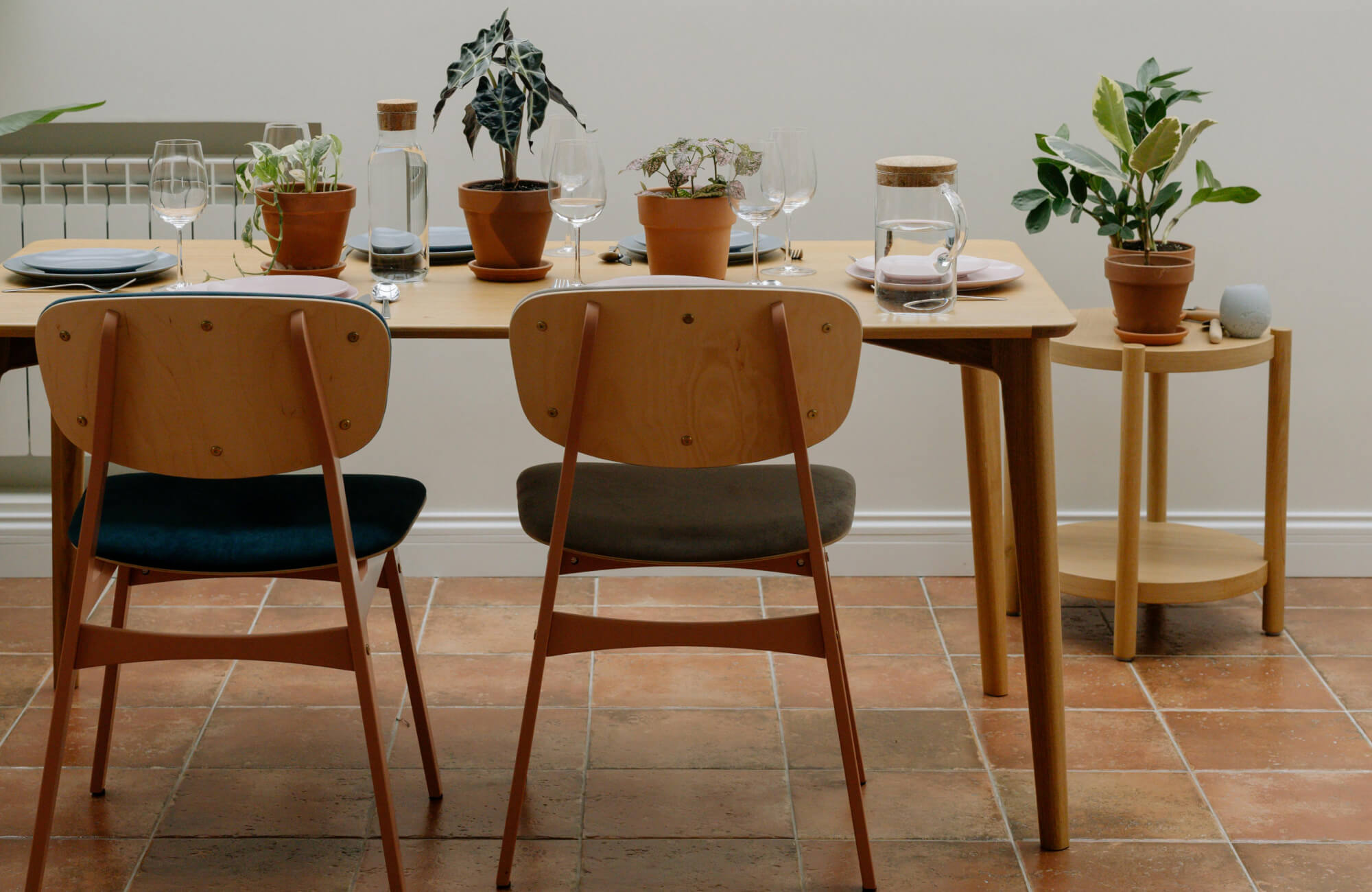 null Dining space with rustic terracotta floor tiles, styled with a wooden table, minimalist chairs, and potted plants.