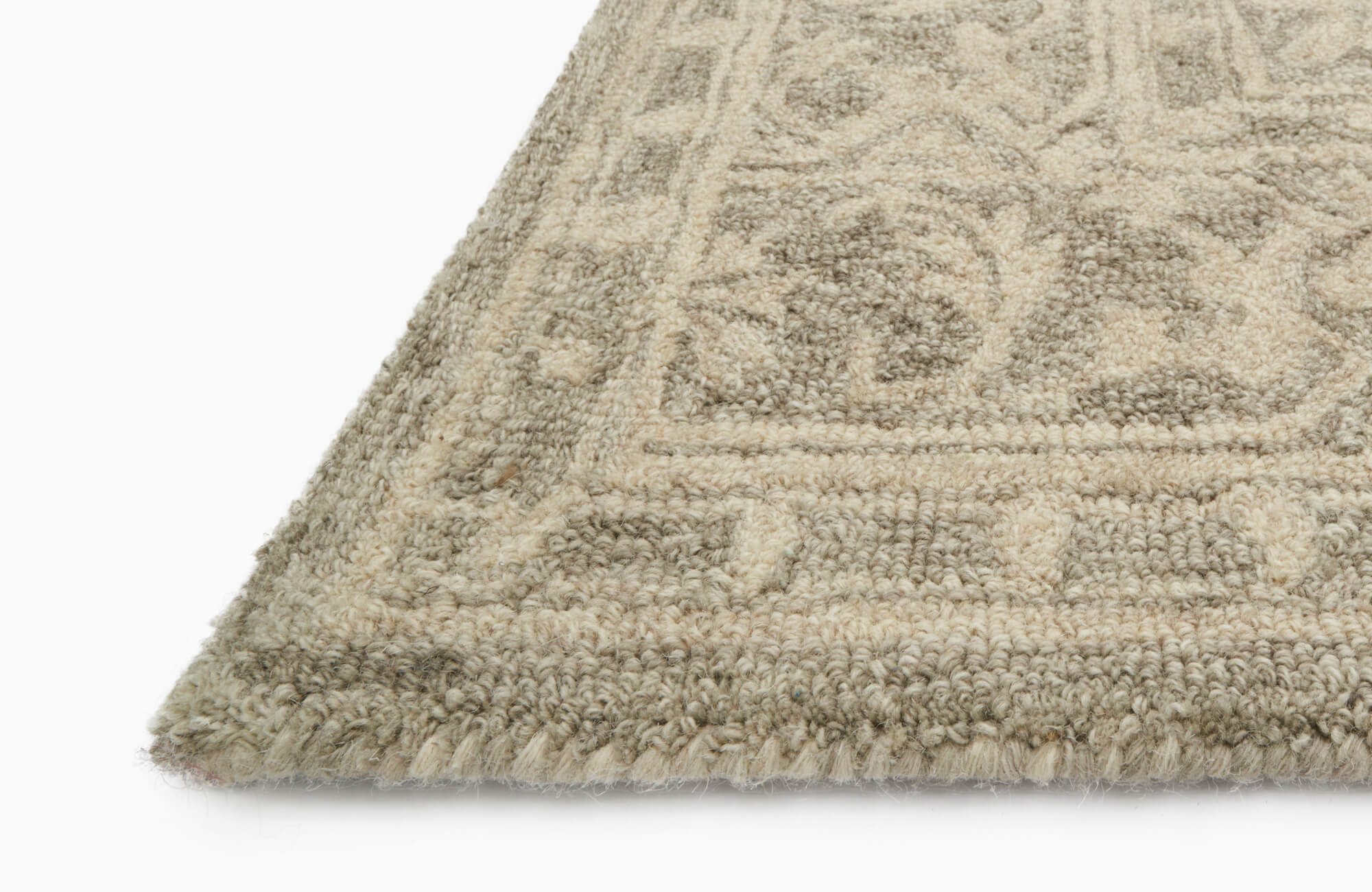 Close-up of a thick, loop-pile wool rug in neutral tones, showcasing its dense weave, textured pattern, and clean edge detail.