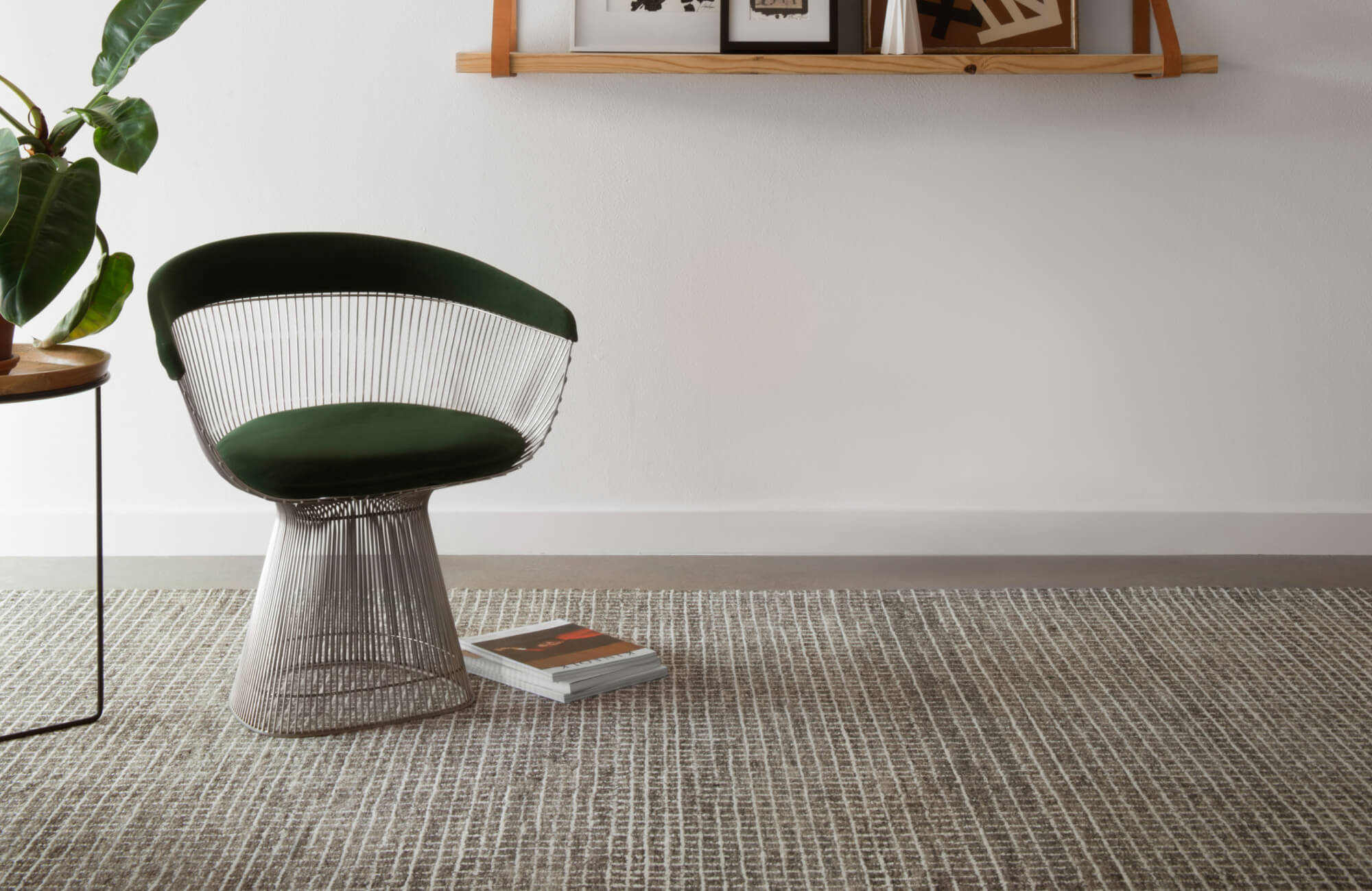 A textured gray wool rug under a green chair creates a relaxed, modern corner with a warm and inviting vibe.