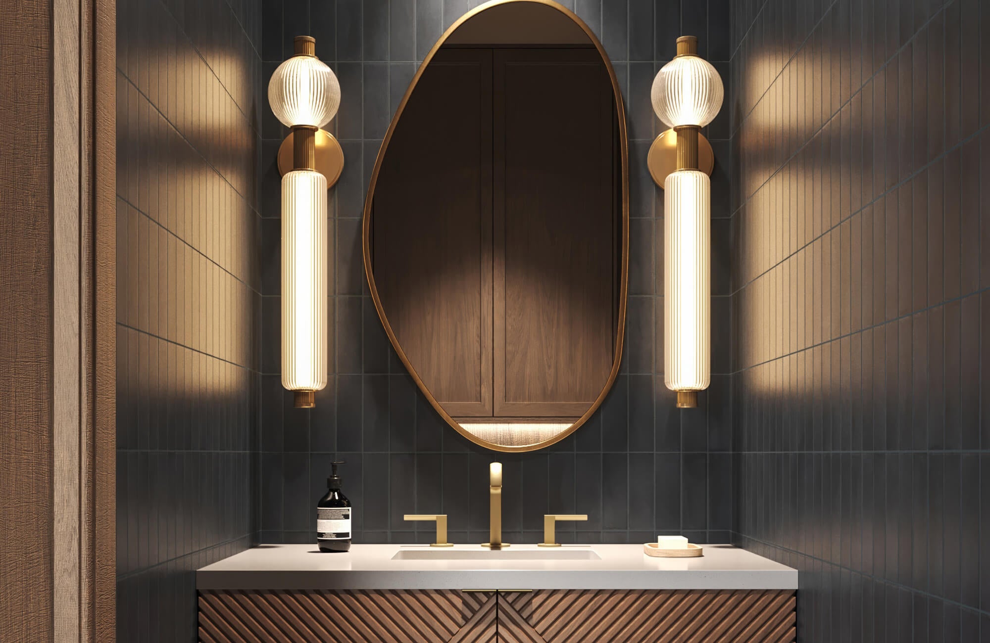 null Sophisticated bathroom with an asymmetrical brass-framed mirror, fluted glass sconces, and dark vertical tiles, creating a warm, moody atmosphere accented by soft golden lighting.