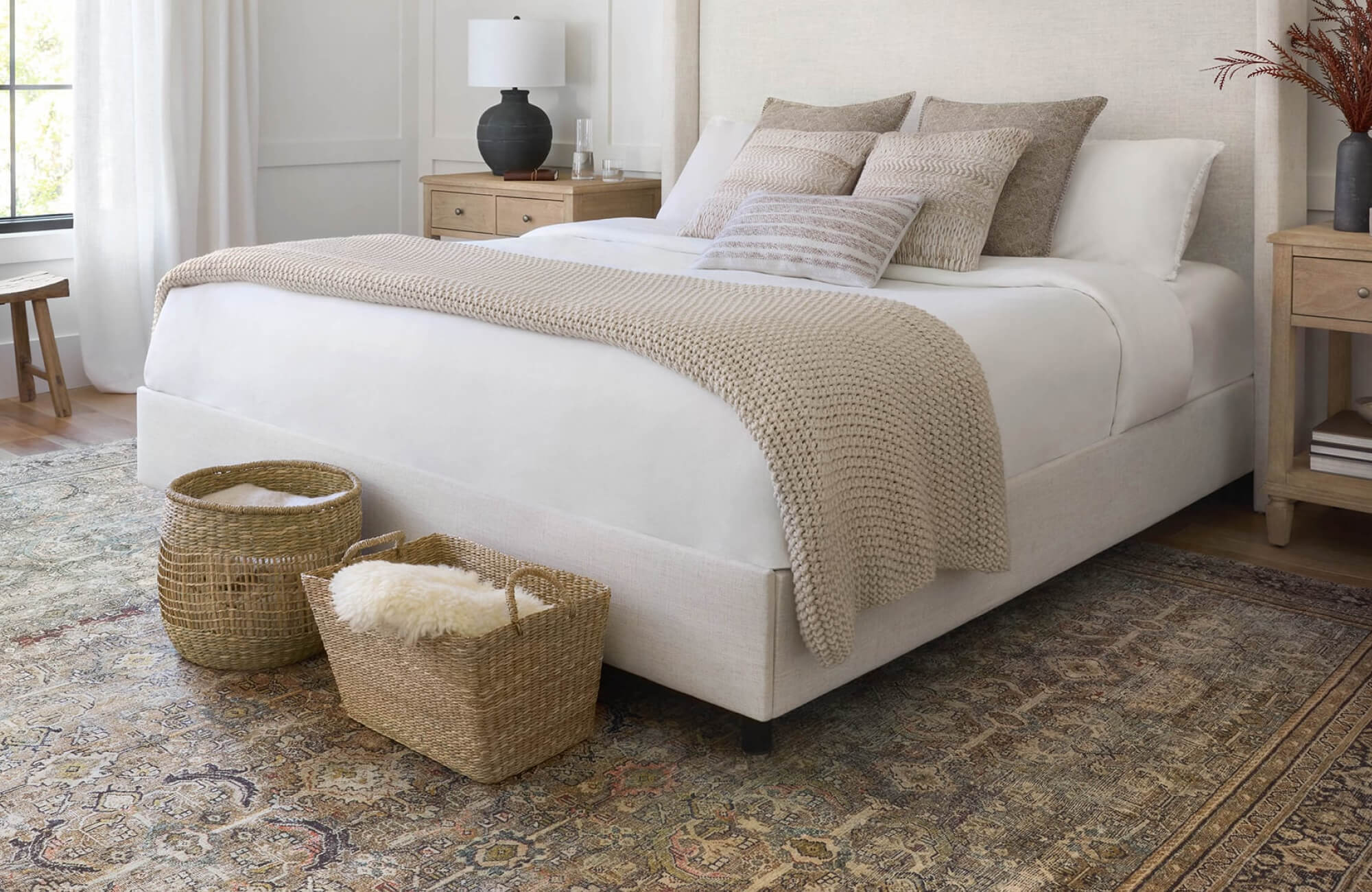 Inviting bedroom with a vintage Persian-style rug adding character, complemented by wooden nightstands topped with modern black ceramic table lamps for balanced lighting.