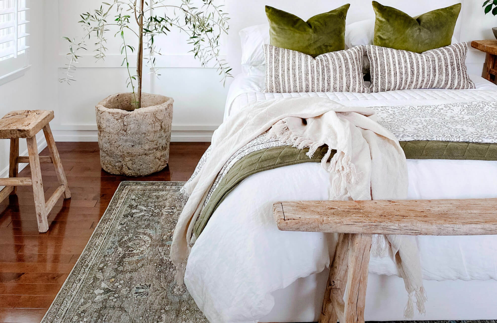 Charming bedroom with a vintage-style rug enhancing rich wood floors, paired with rustic wooden accents and natural light for a warm, organic feel.
