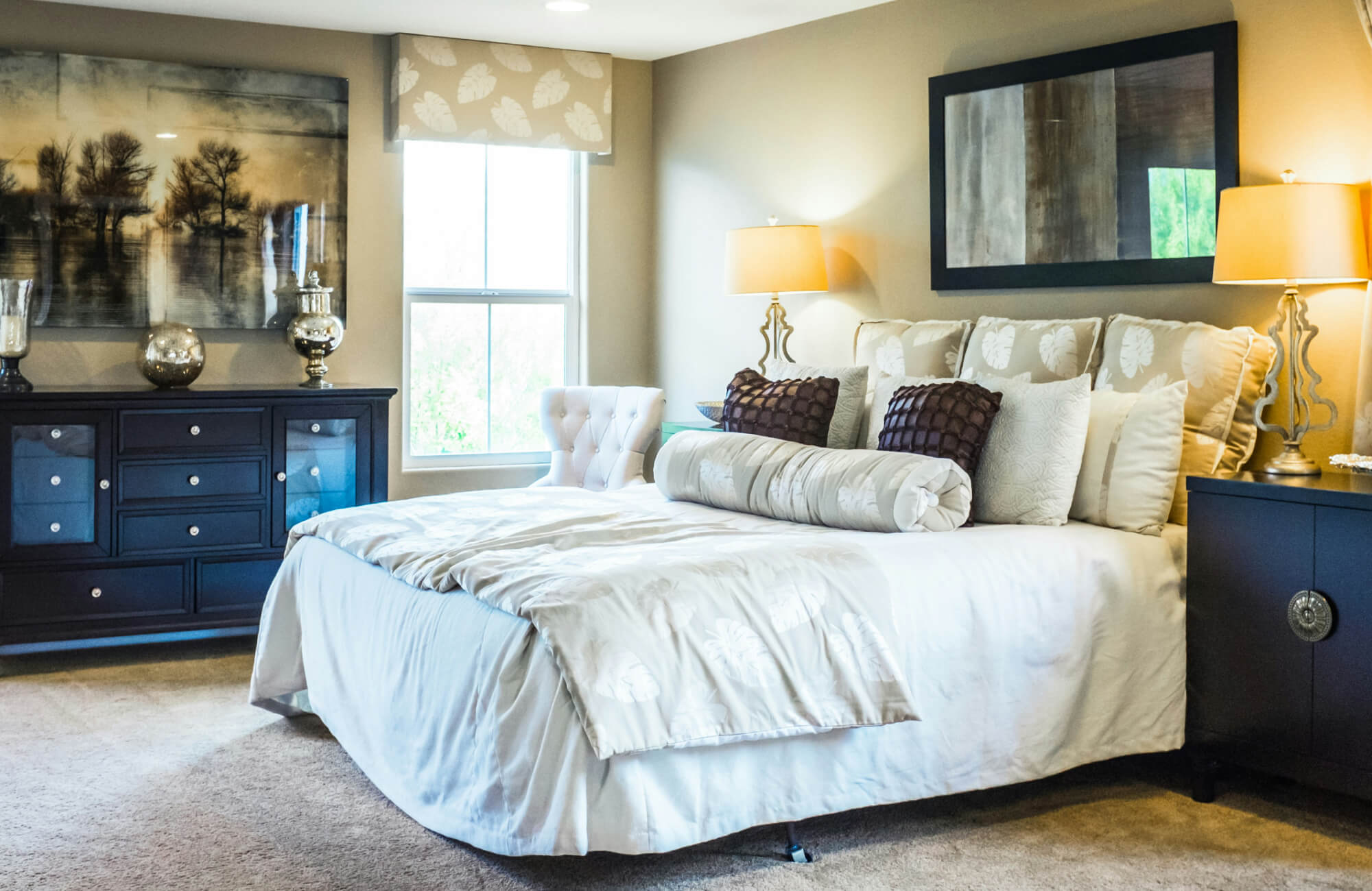 Elegant bedroom with a plush beige carpet complementing dark wood furniture, illuminated by matching gold table lamps with soft fabric shades for a warm, inviting glow.