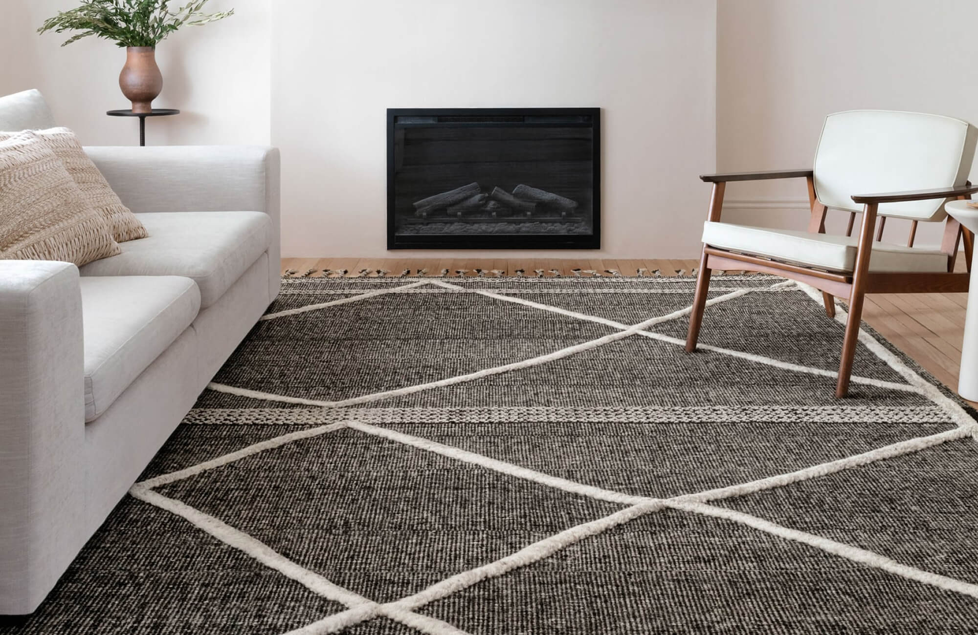 Minimalist living room with a bold brown rug featuring oversized white geometric lines, adding contrast and texture to the neutral space.