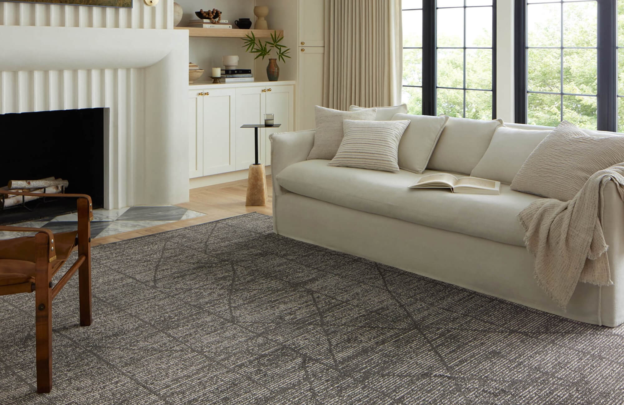 Bright living room with a cream sofa and fireplace, grounded by a patterned brown rug that adds warmth and subtle texture to the space.