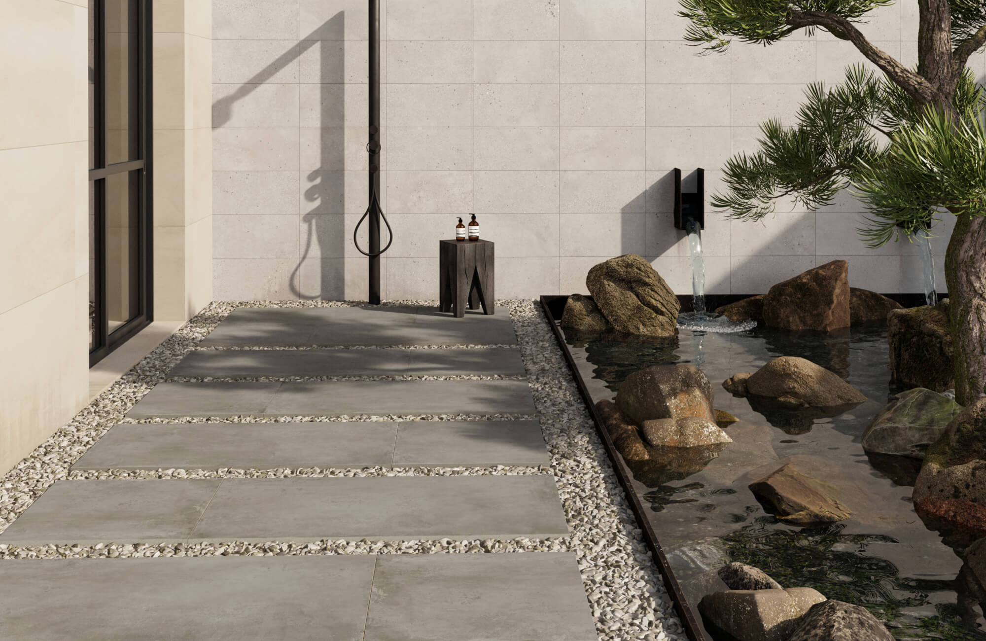 null Zen-inspired patio with concrete look porcelain pavers and gravel joints beside a tranquil rock-lined water feature and outdoor shower.