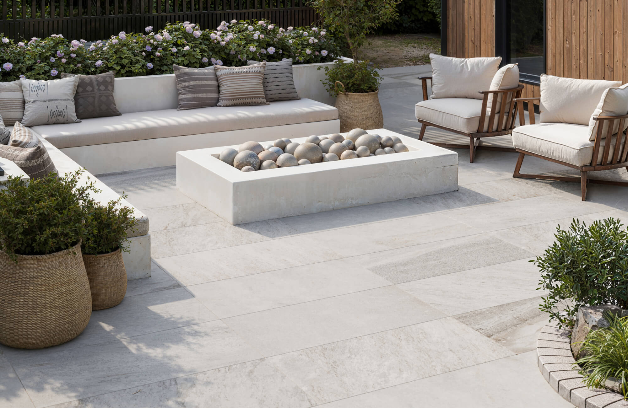 null Modern patio with creamy porcelain tile pavers, built-in bench seating, and a sculptural stone fire feature for a serene, styled retreat