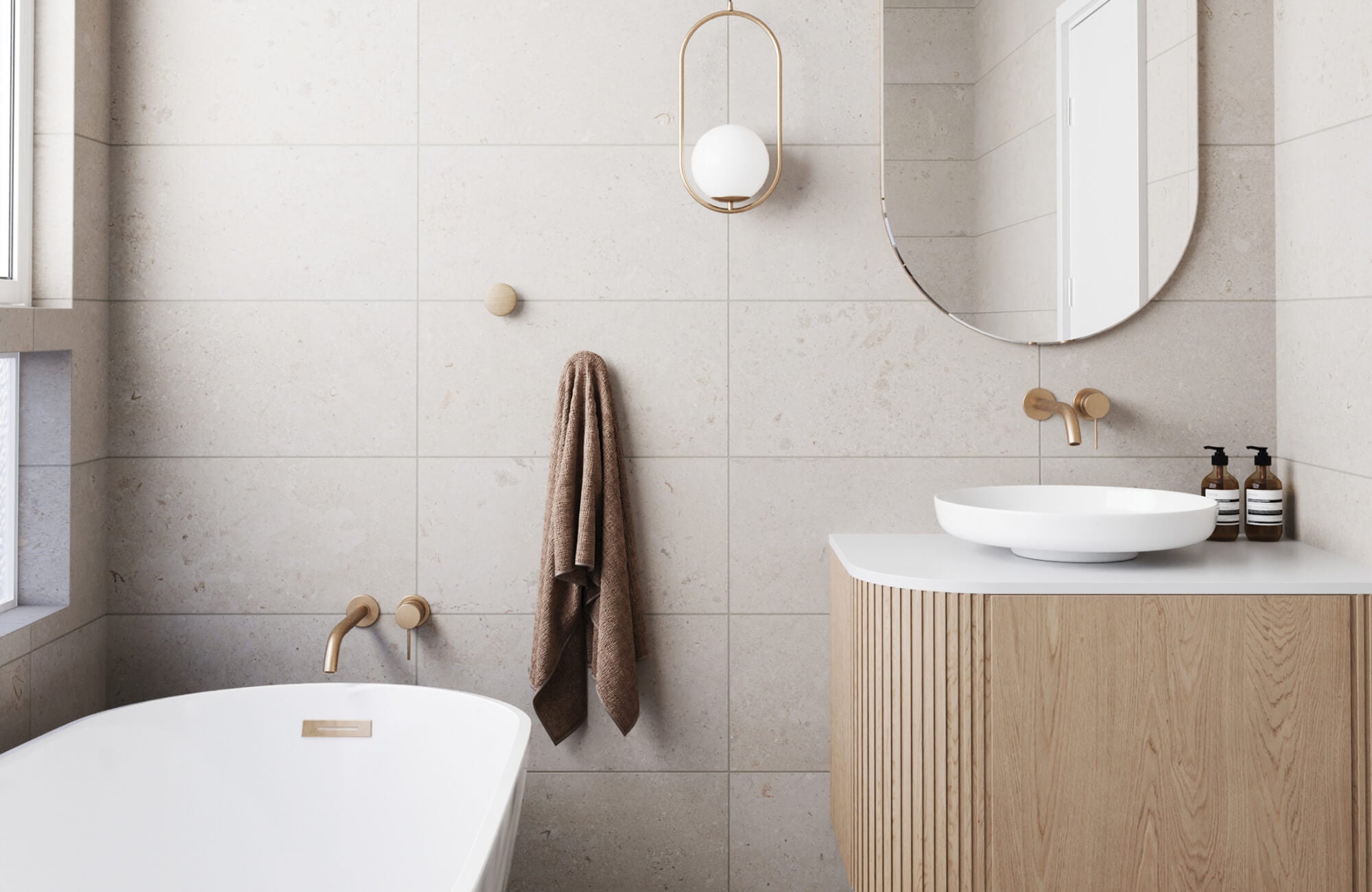 Soft-toned bathroom featuring minimalist large wall tiles and natural wood vanity with rounded mirror.