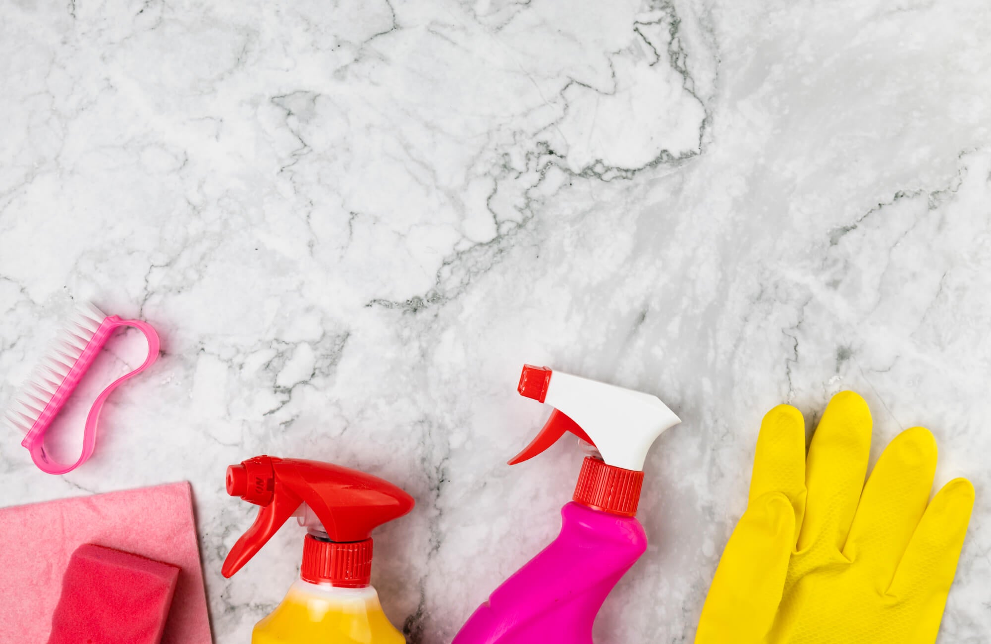 null Marble surface with cleaning sprays, gloves, sponge, and scrub brush arranged for stone care and maintenance.