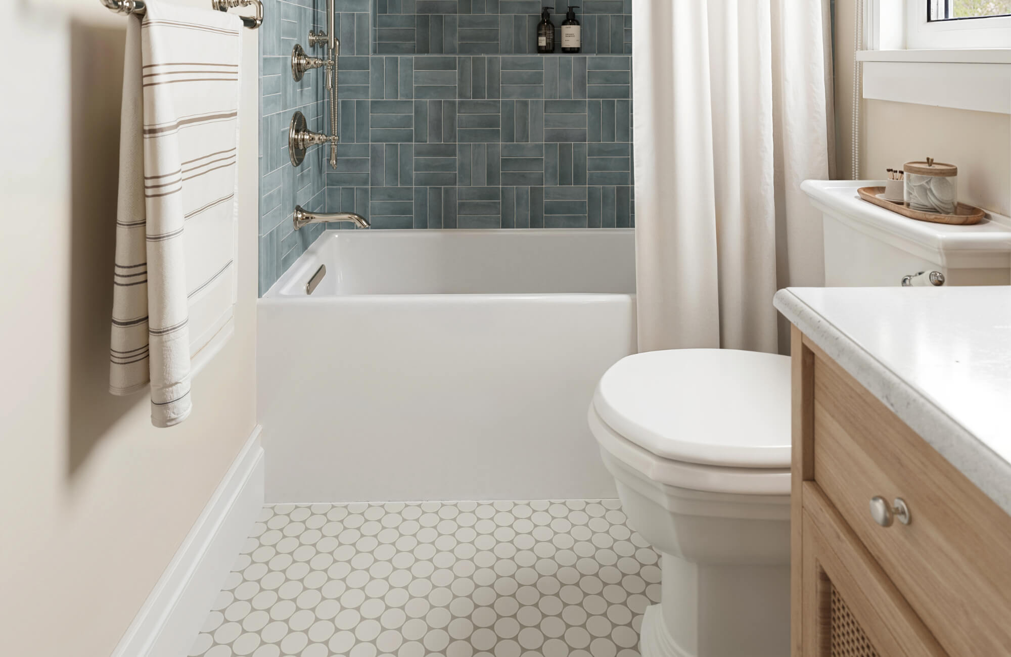 Small bathroom featuring white penny round mosaic floor tiles, a deep soaking tub, and blue subway wall tiles in a stacked herringbone pattern.