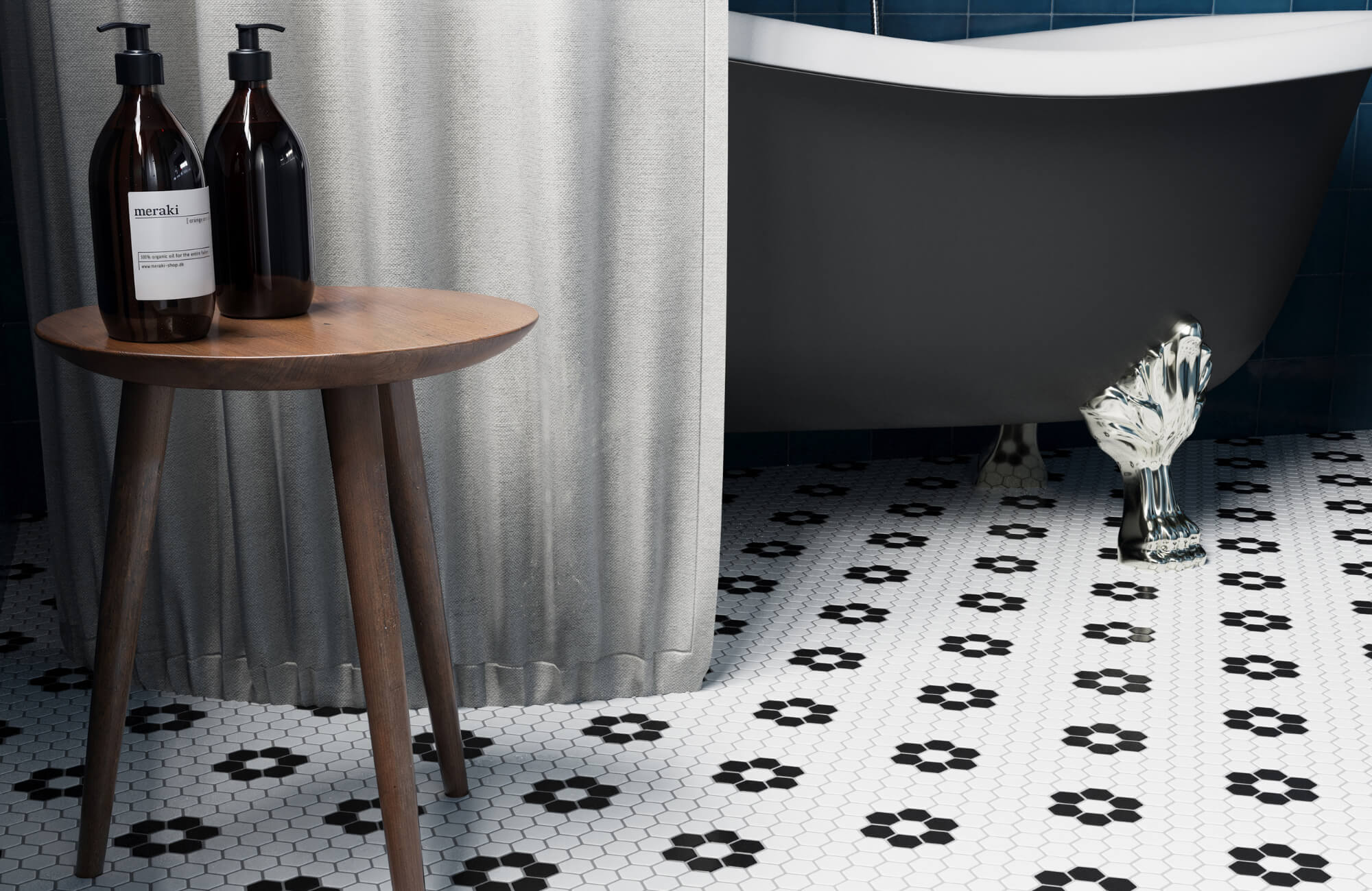 Vintage-style bathroom with white hexagon mosaic floor tiles featuring black floral patterns, a clawfoot tub, and a wooden side table.