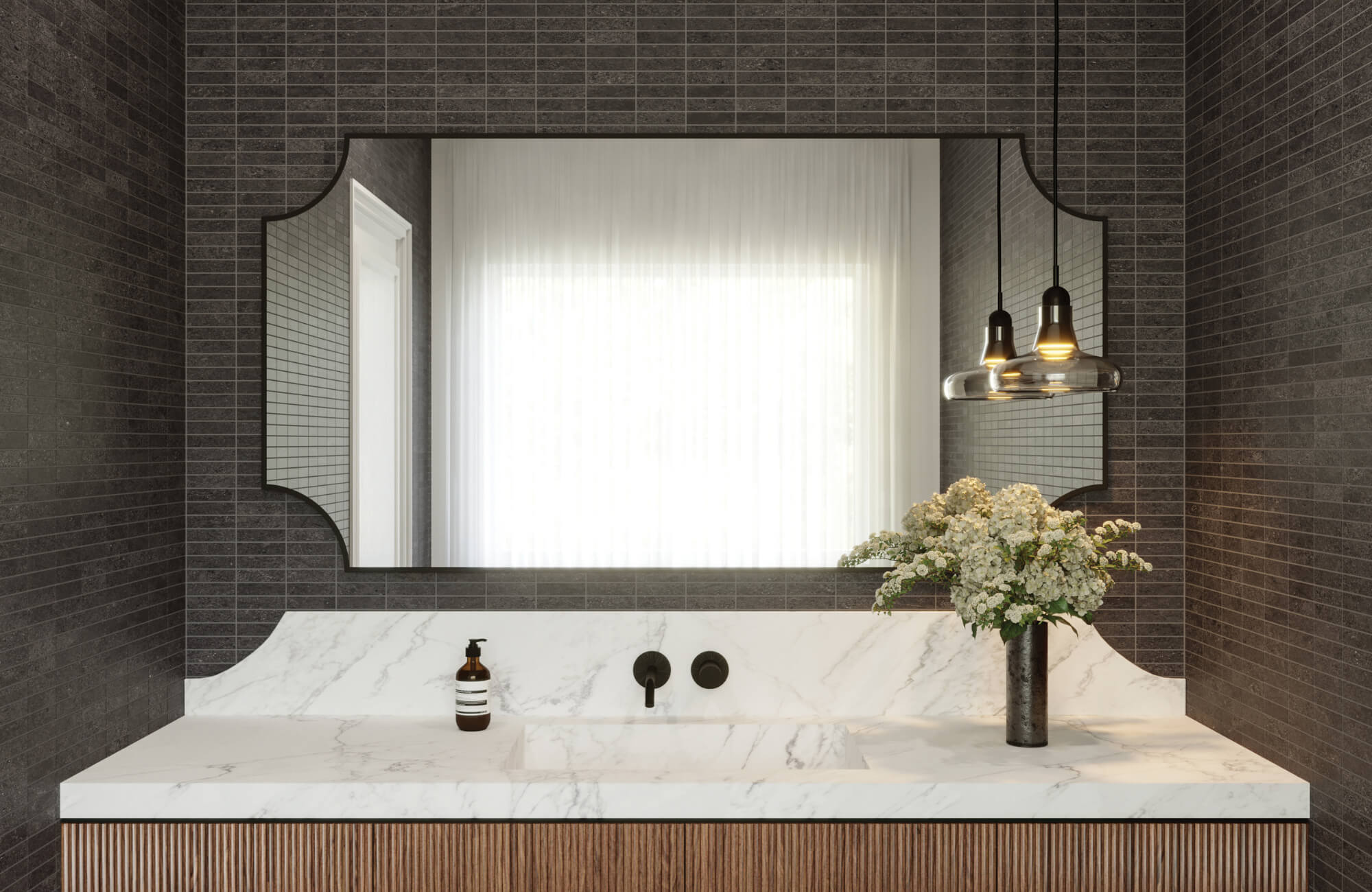 Elegant bathroom with dark linear mosaic wall tiles, a marble countertop, fluted wood vanity, and a custom mirror with pendant lighting.