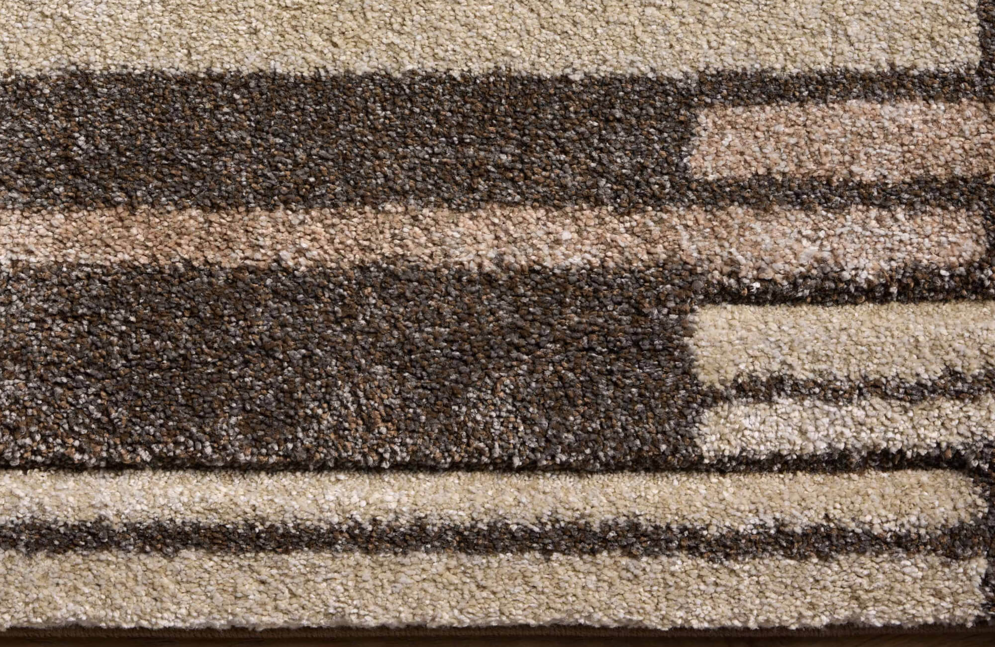 Textured polypropylene area rug with geometric stripes in earthy tones of brown, beige, and cream for a warm, modern look.