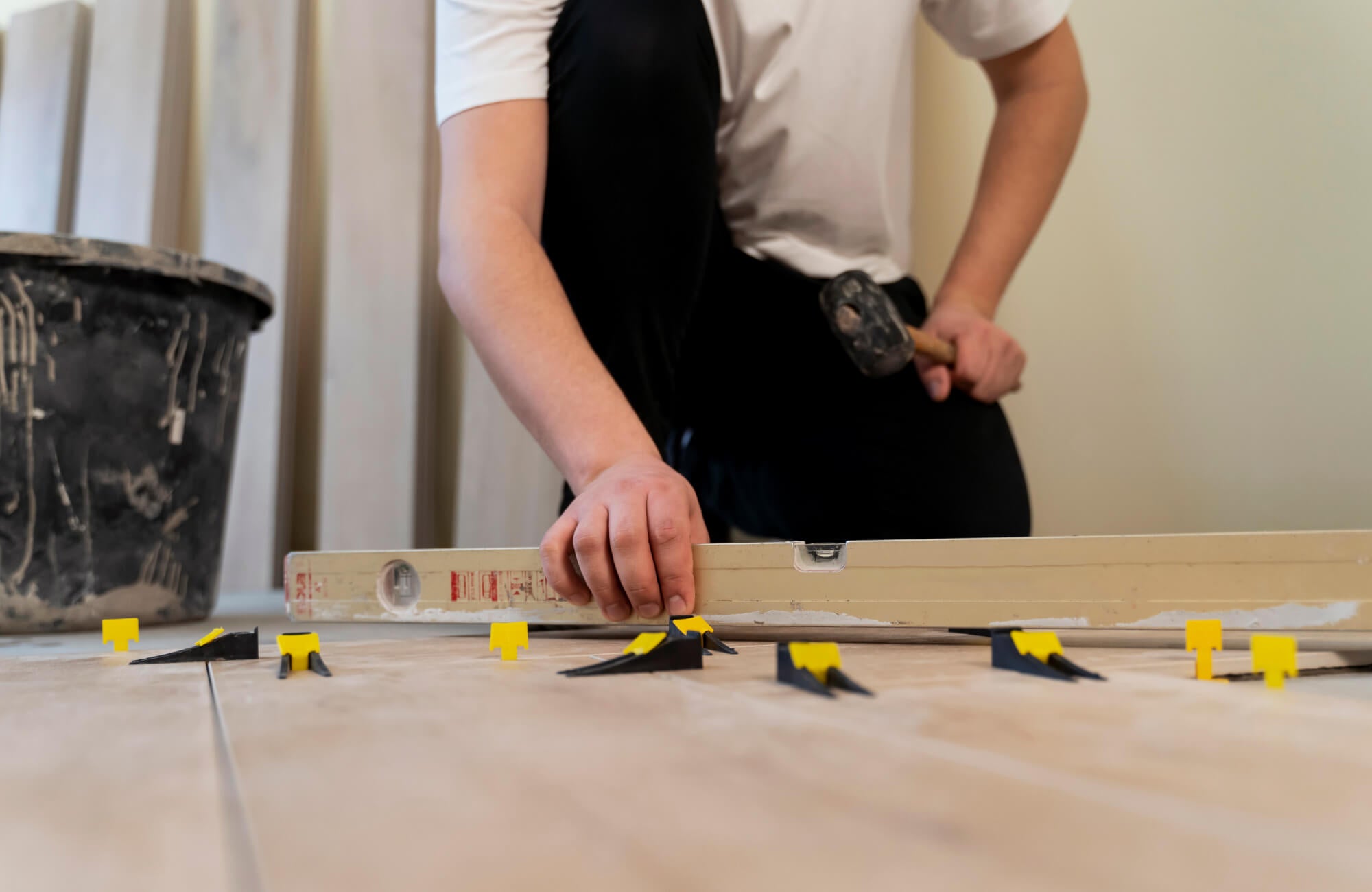 Close-up of tile leveling clips and spacers being adjusted to keep the flooring straight and even.