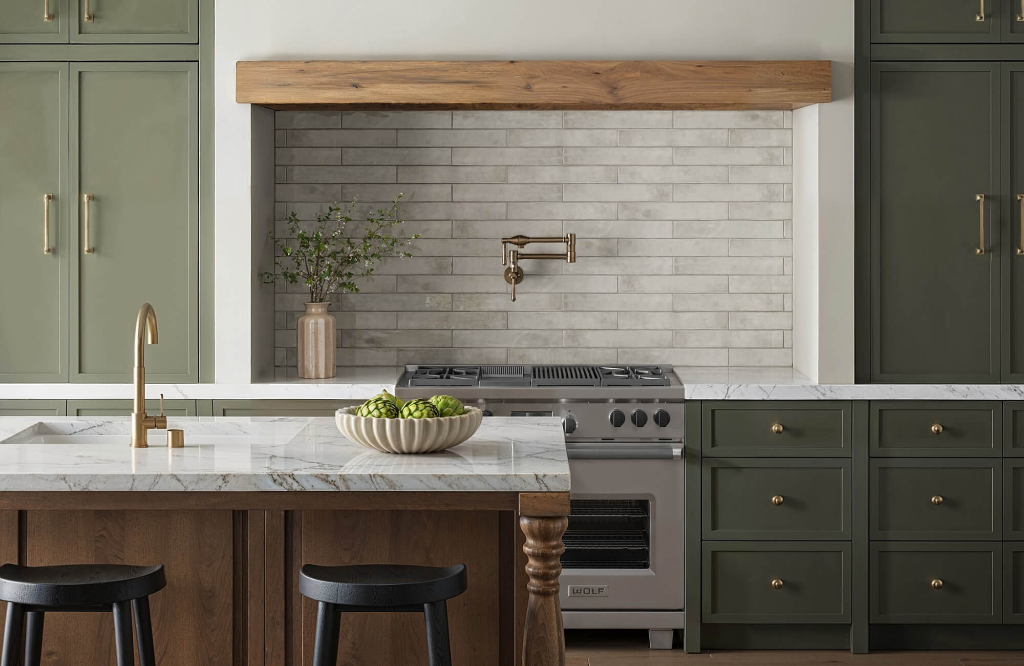 null Modern kitchen with green cabinets, marble countertops, wood accents, and a gray tile backsplash behind a stainless steel stove.
