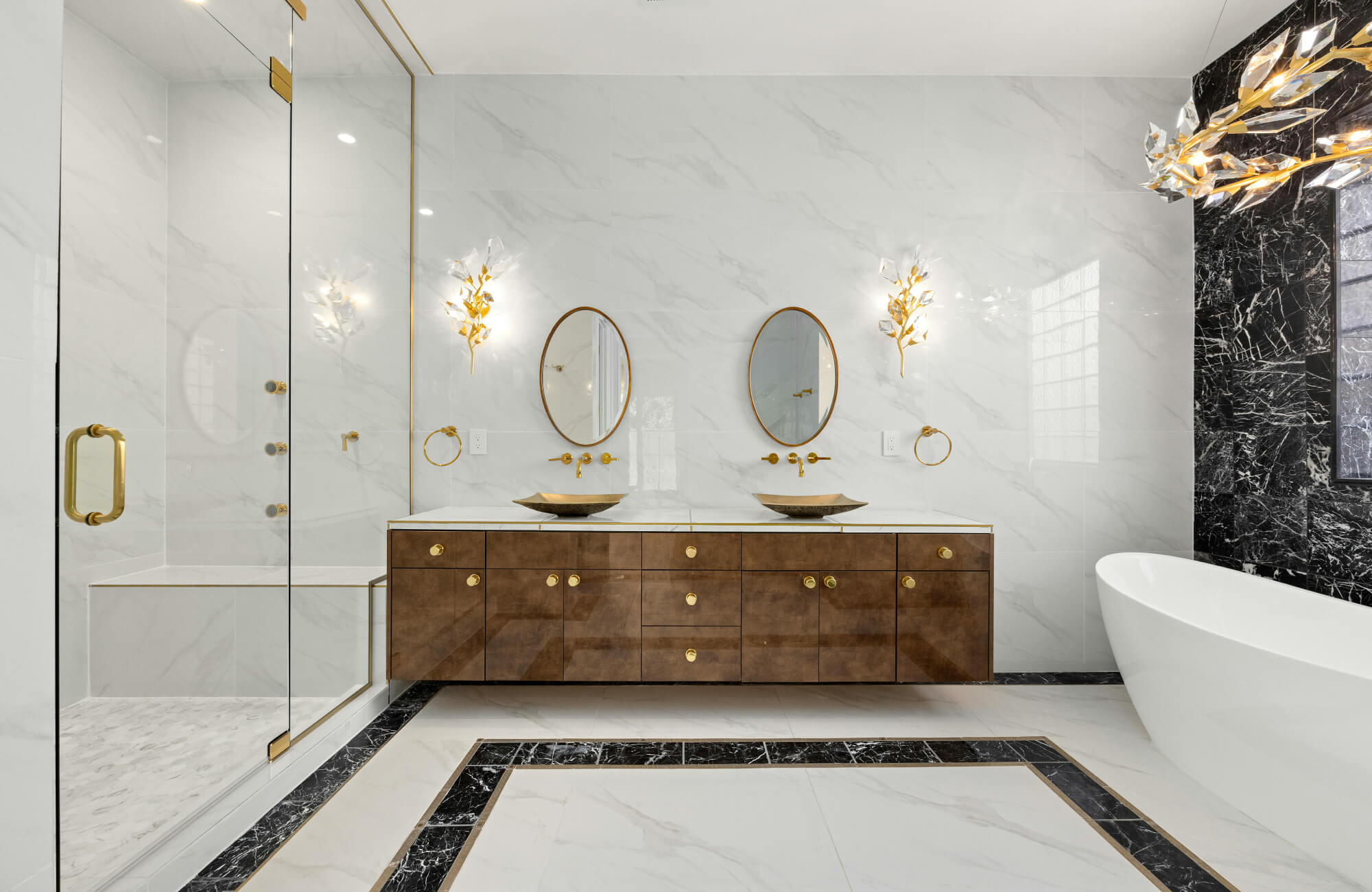 null Modern marble bathroom with large Carrara-style wall tiles, double vanity with gold accents, freestanding tub, and glass shower.