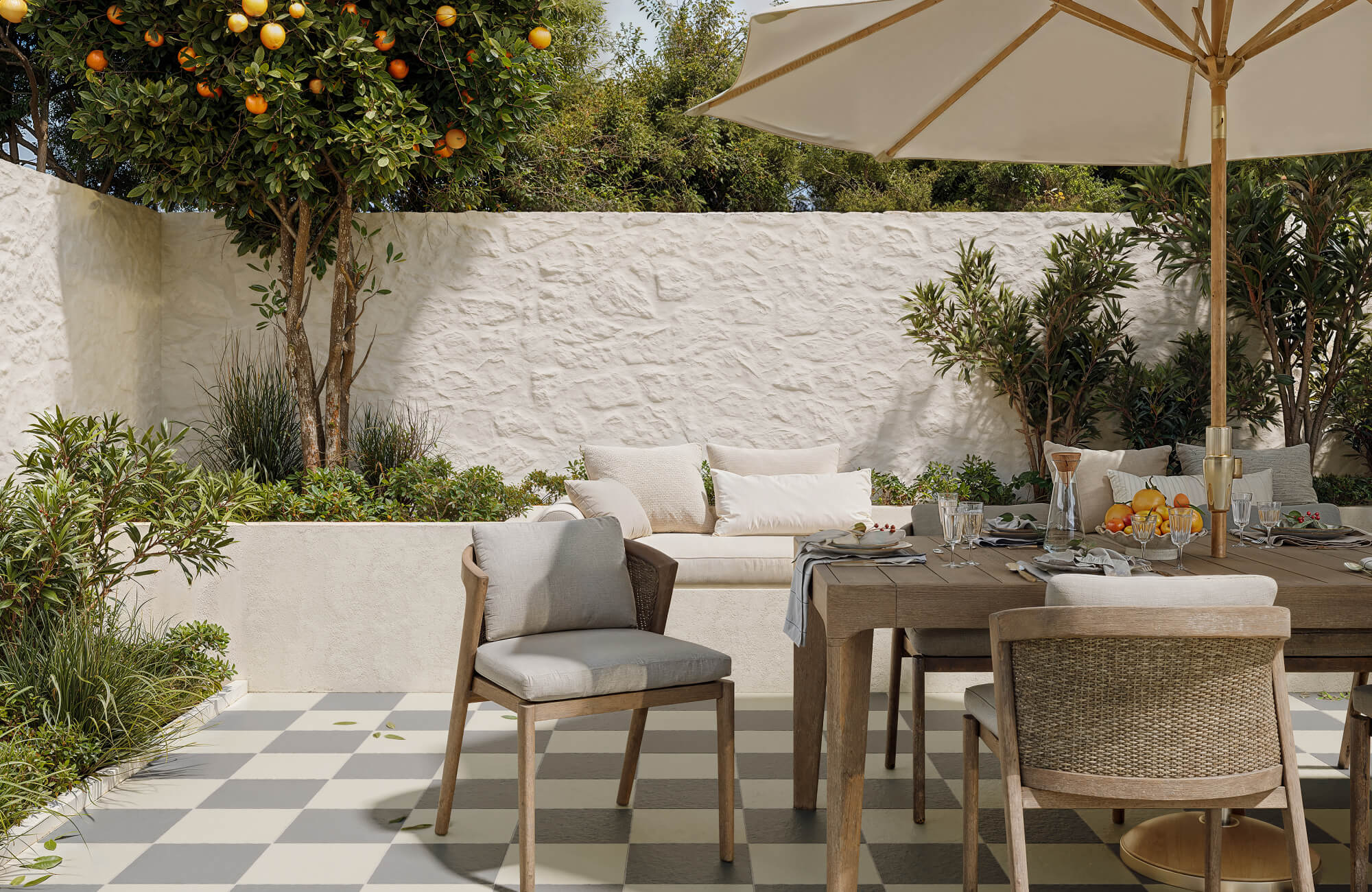 null Charming courtyard with grey and cream checkerboard tiles, featuring a cozy dining area and lush citrus tree.